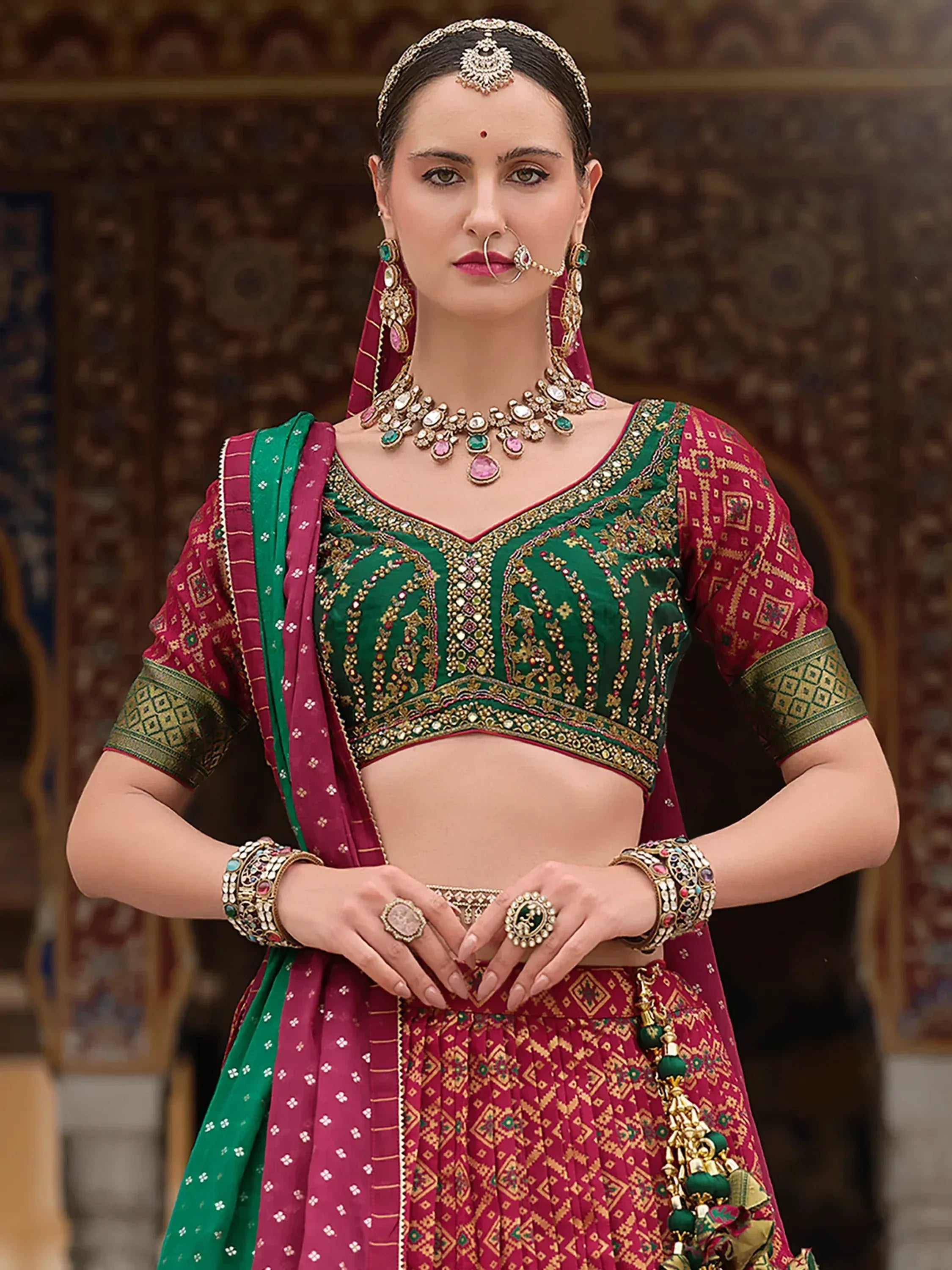 Green and maroon designer lehenga choli with heavy embroidery and traditional Indian jewelry