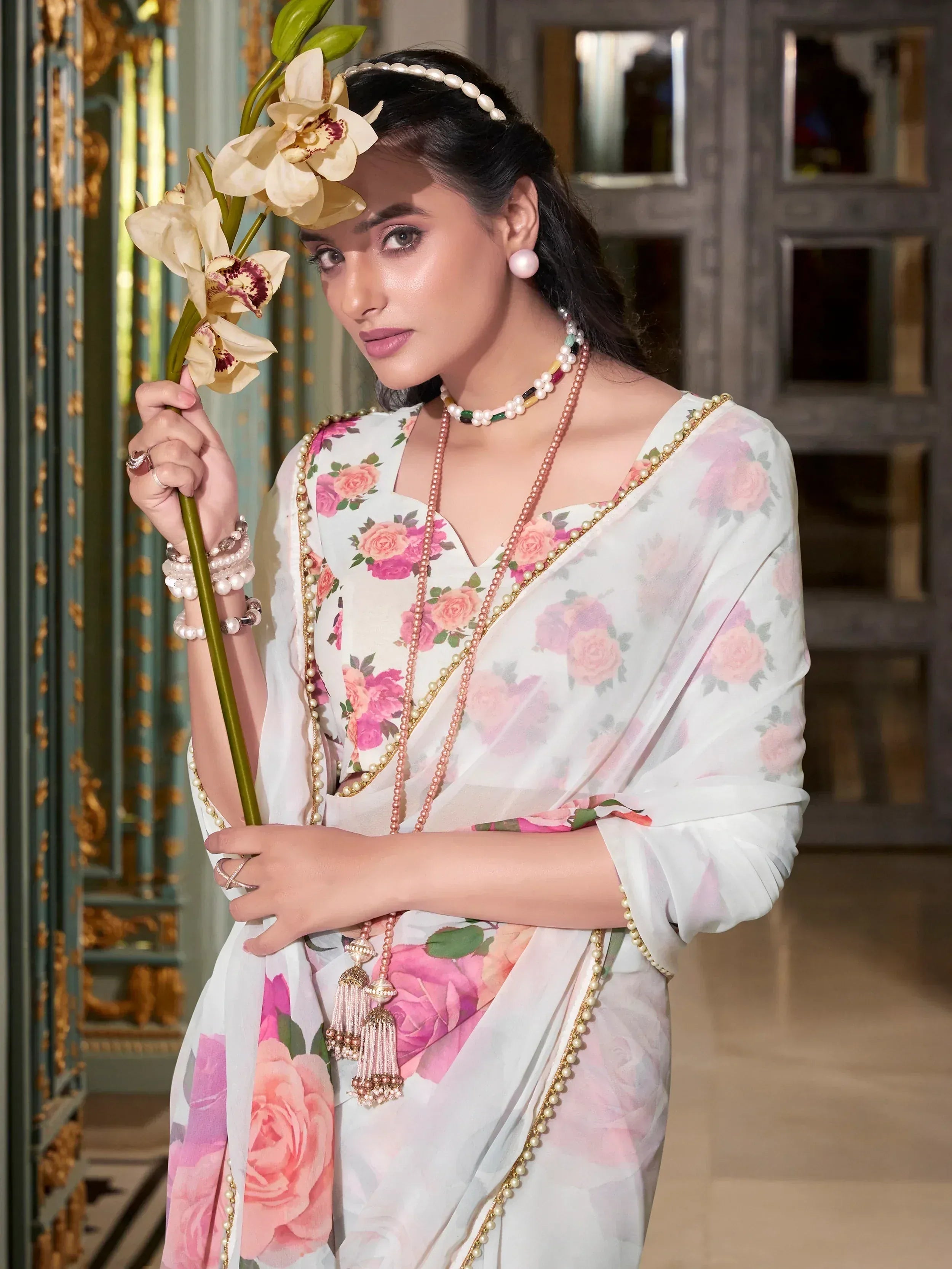 Woman in floral print ethnic gown with pearl jewelry and orchid, perfect for Indian occasions