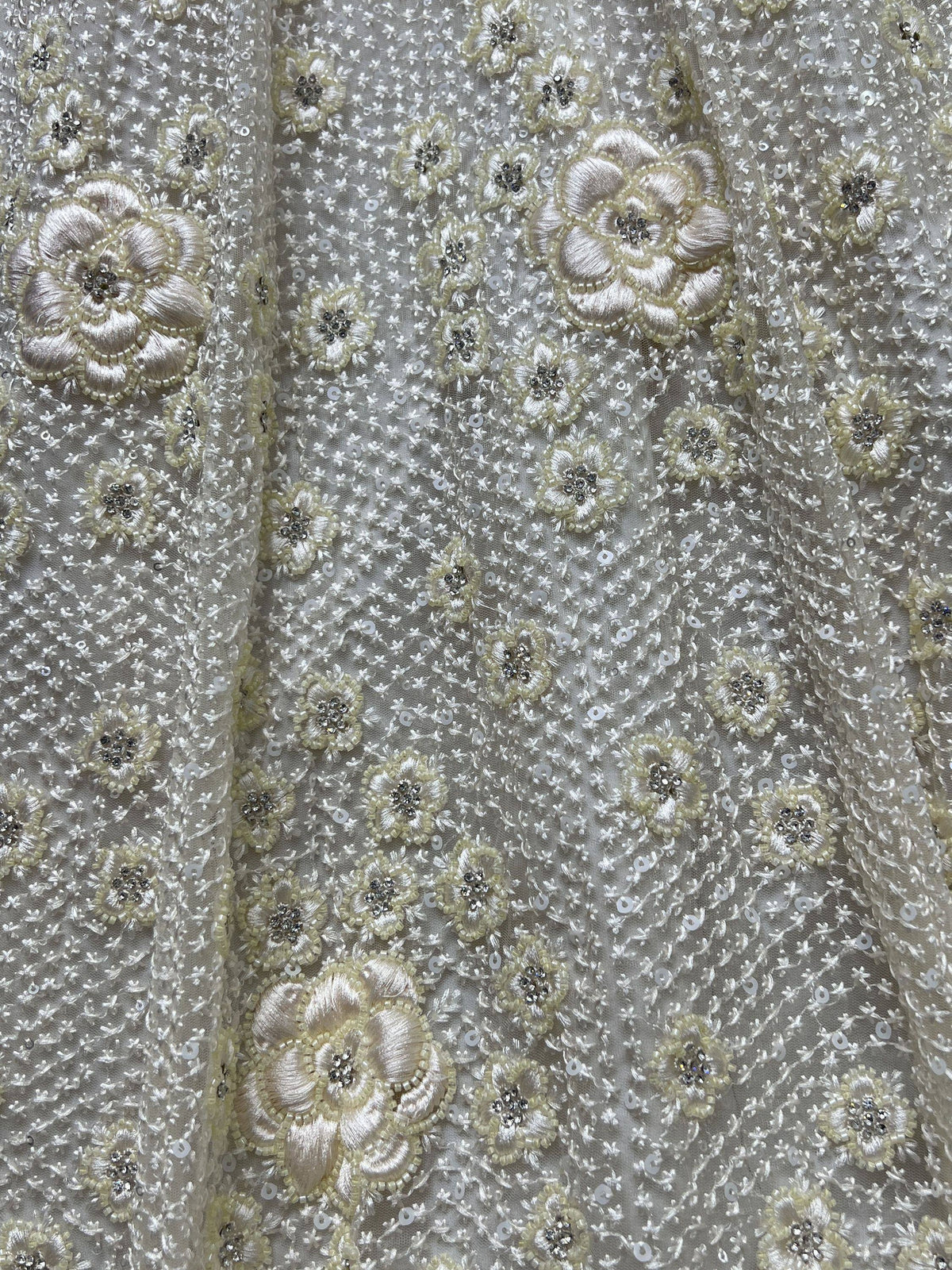 Elegant ivory ethnic wear fabric with floral embroidery, sequins, and beadwork for designer lehenga or gown.