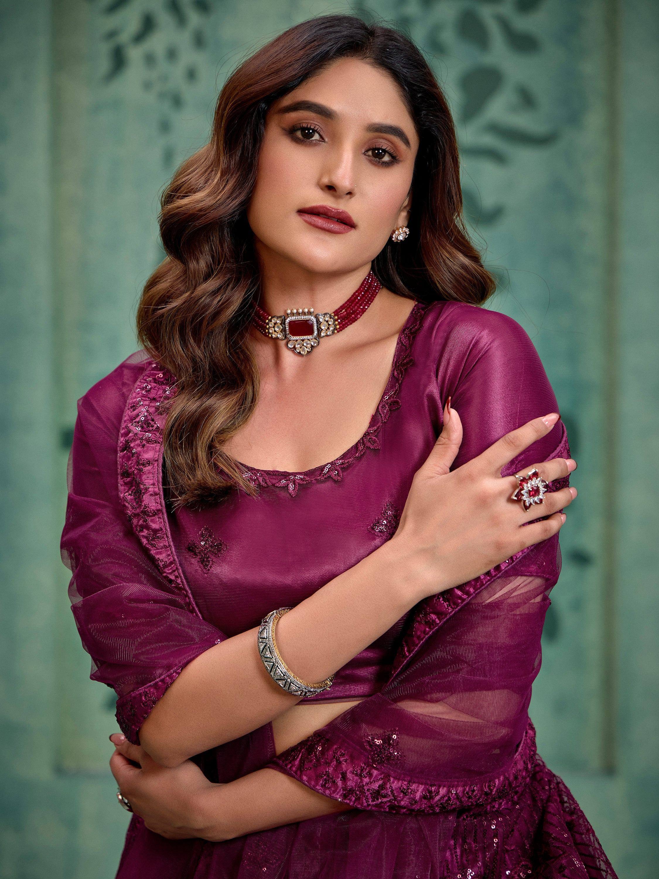 Woman in elegant maroon ethnic gown with sequin detailing, paired with traditional jewelry for festive occasions