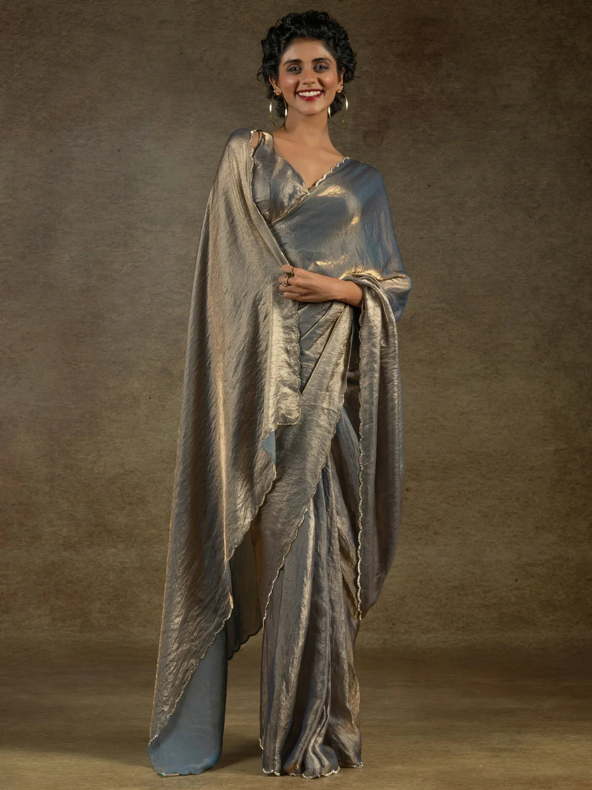 Woman in shimmering grey metallic saree with scalloped gold trim, elegant Indian ethnic wear