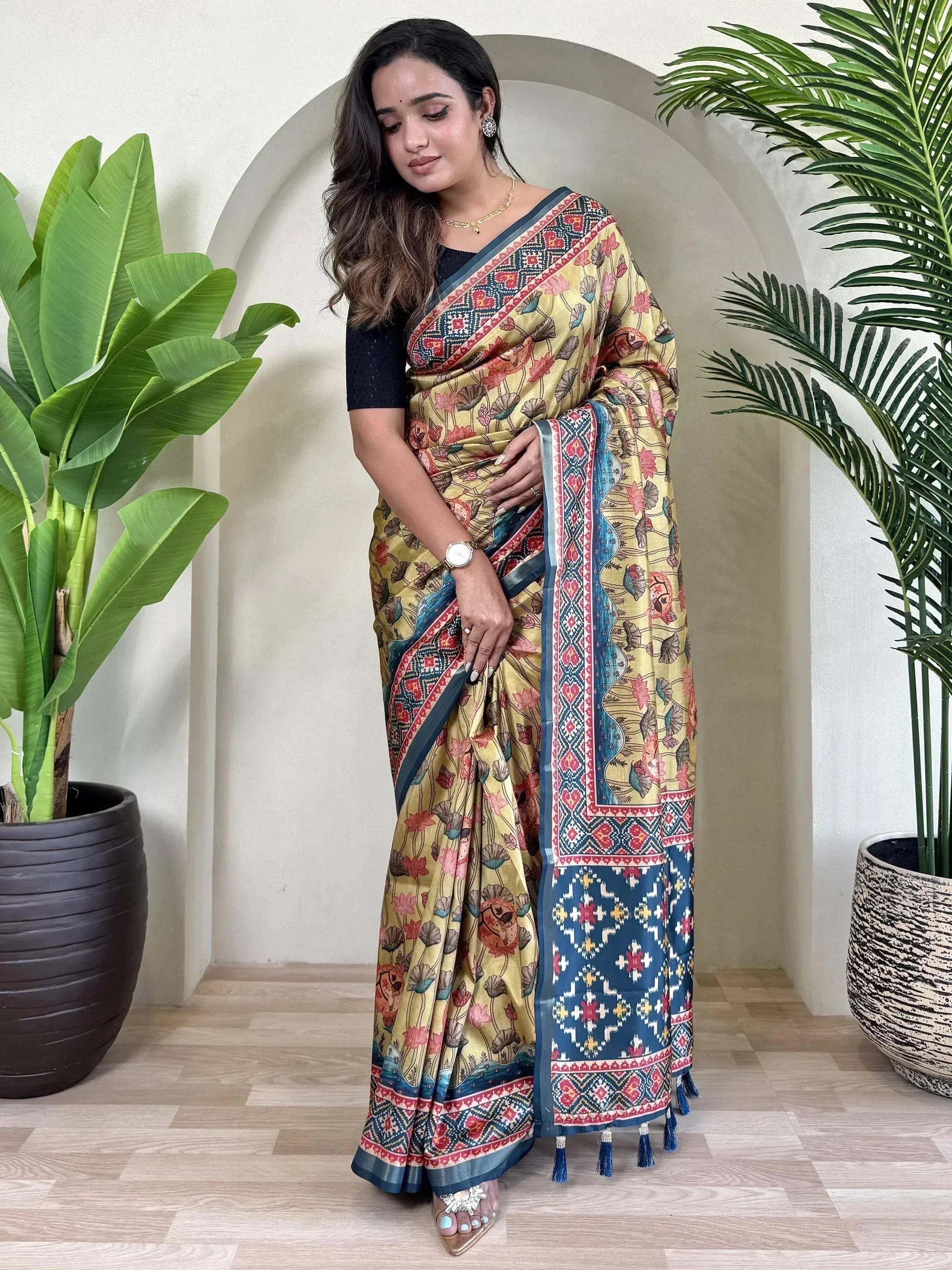 Yellow floral saree with blue border and tassels, styled with black blouse for ethnic wear