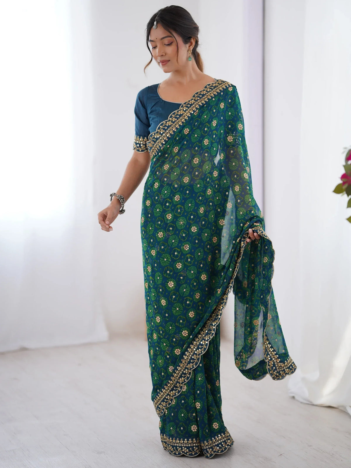Woman in teal green floral printed saree with gold embroidery, perfect for Indian ethnic wear occasions.