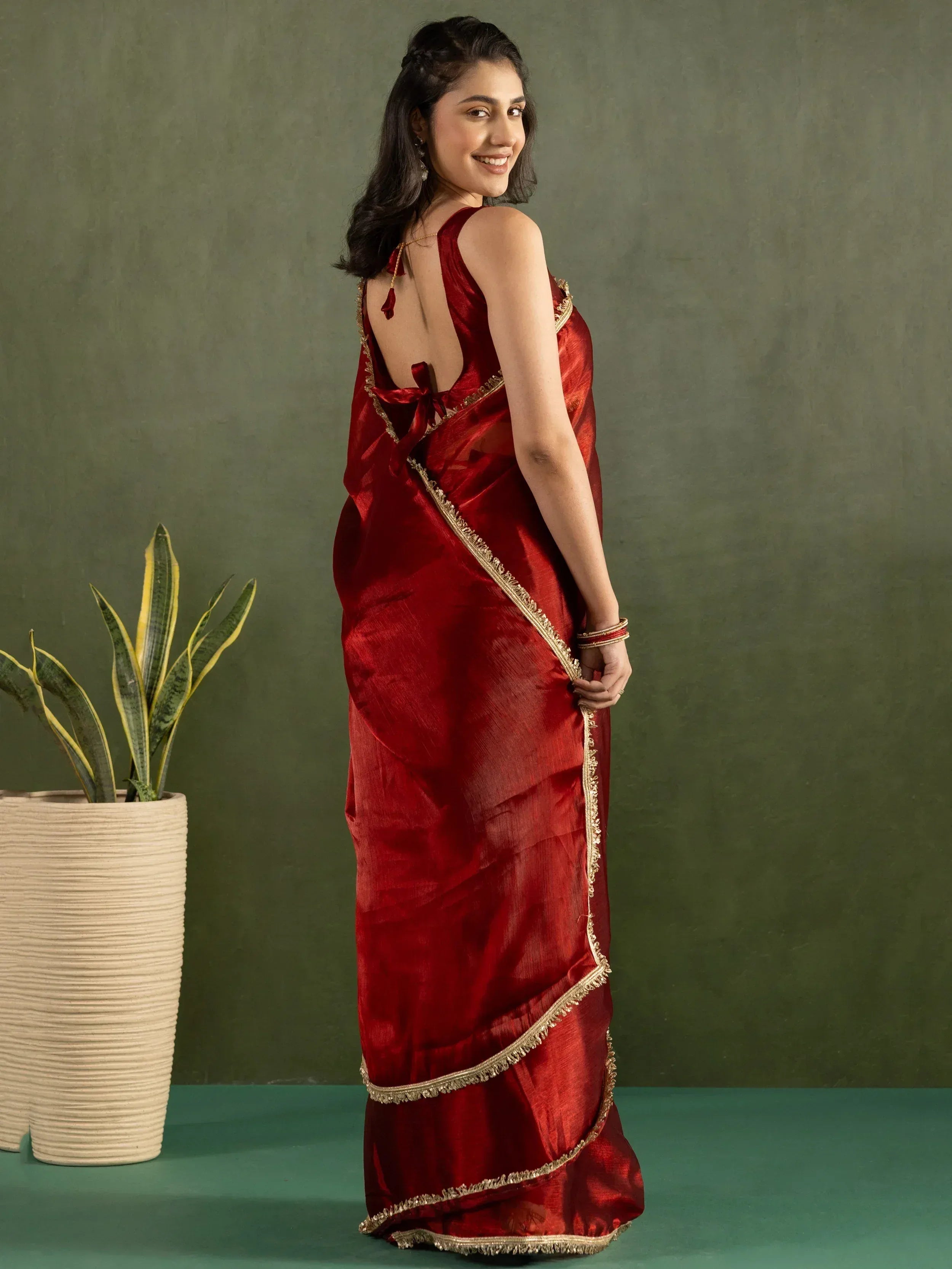 Woman in maroon saree with gold trim, backless blouse, ethnic wear for Indian occasions