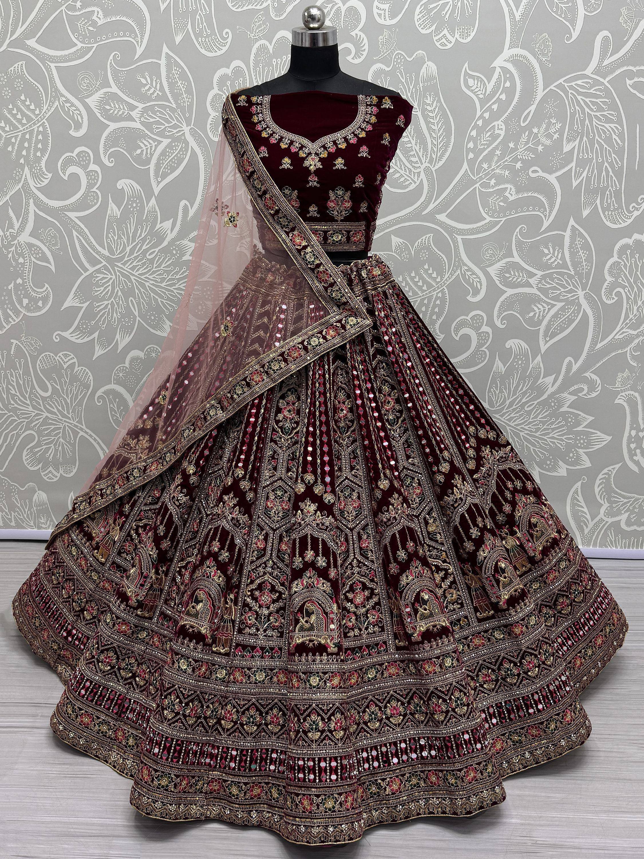 Maroon velvet designer lehenga choli with heavy gold embroidery and mirror work, perfect for Indian weddings.