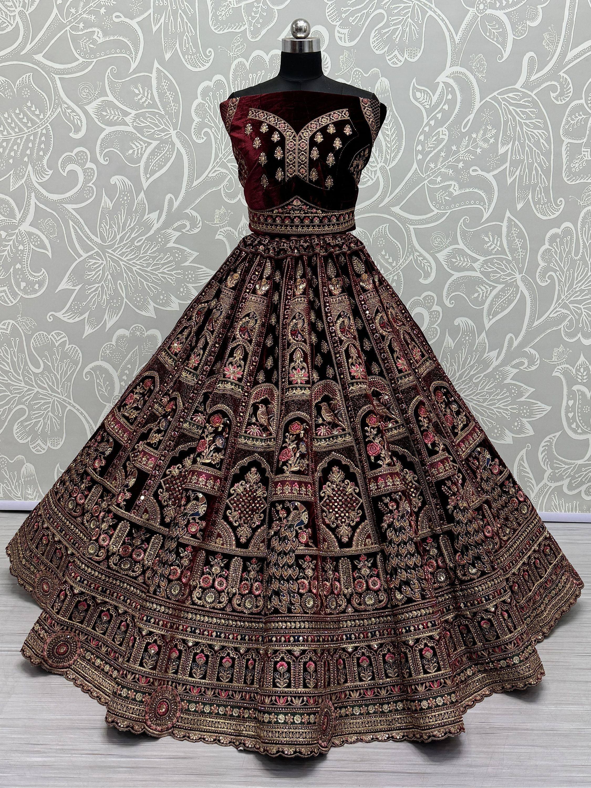 Maroon velvet designer lehenga choli with heavy gold embroidery and floral motifs, perfect for Indian weddings.