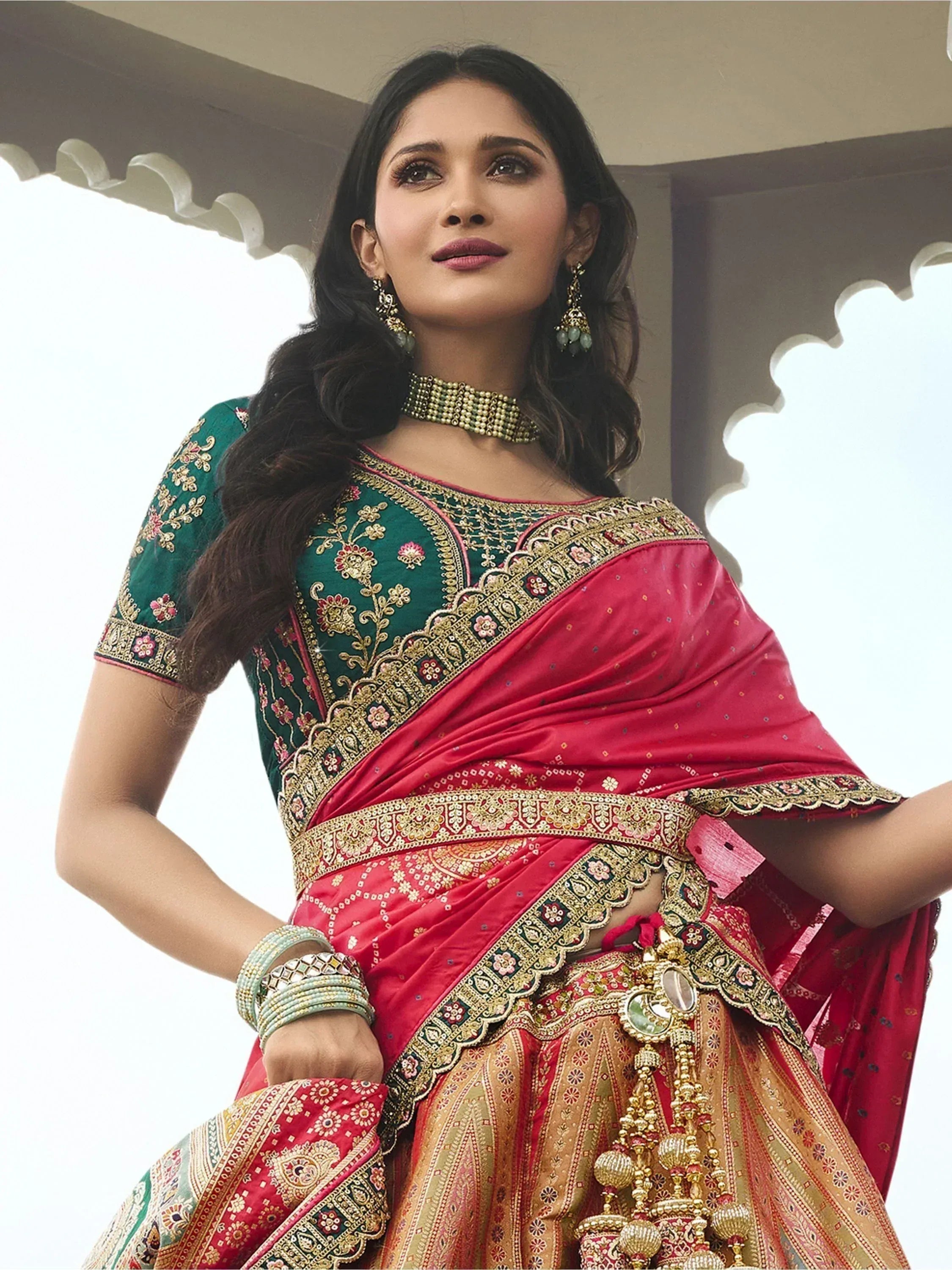 Woman in red and green embroidered lehenga choli with gold detailing, traditional Indian ethnic wear