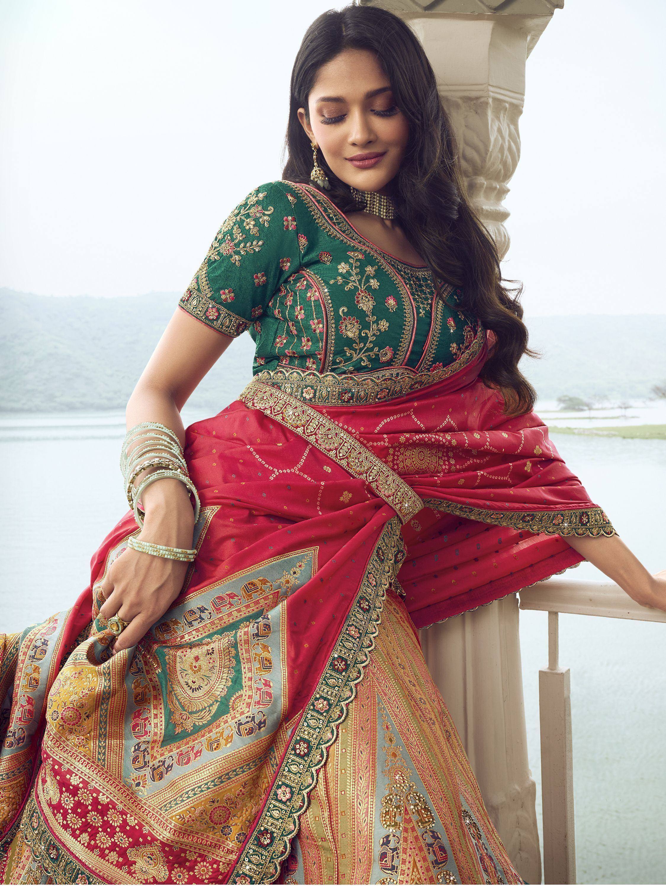 Woman in elegant red and green embroidered saree with gold detailing, perfect for Indian ethnic occasions.
