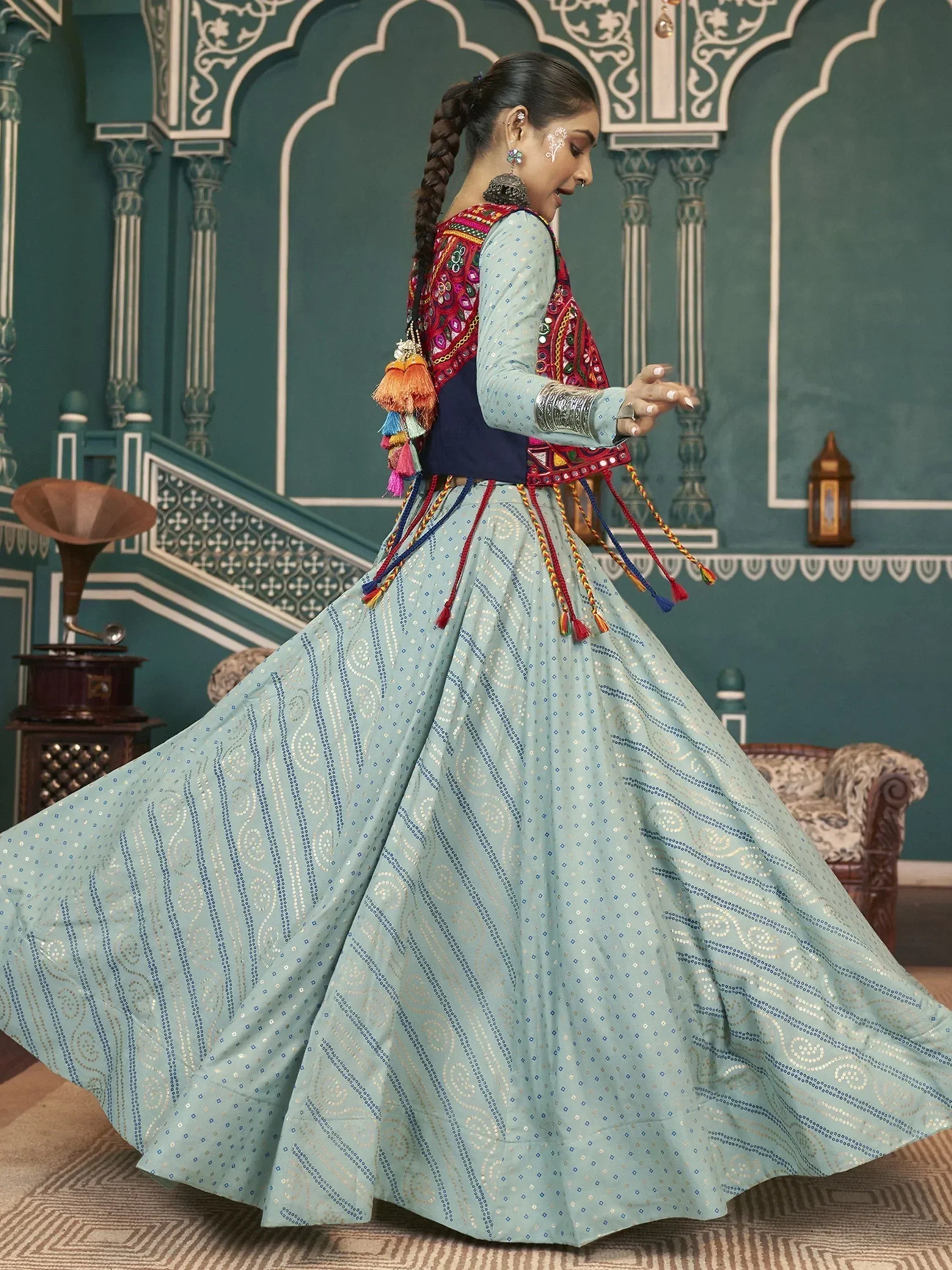 Woman in light blue embroidered lehenga with colorful mirror work blouse, twirling in traditional Indian ethnic wear