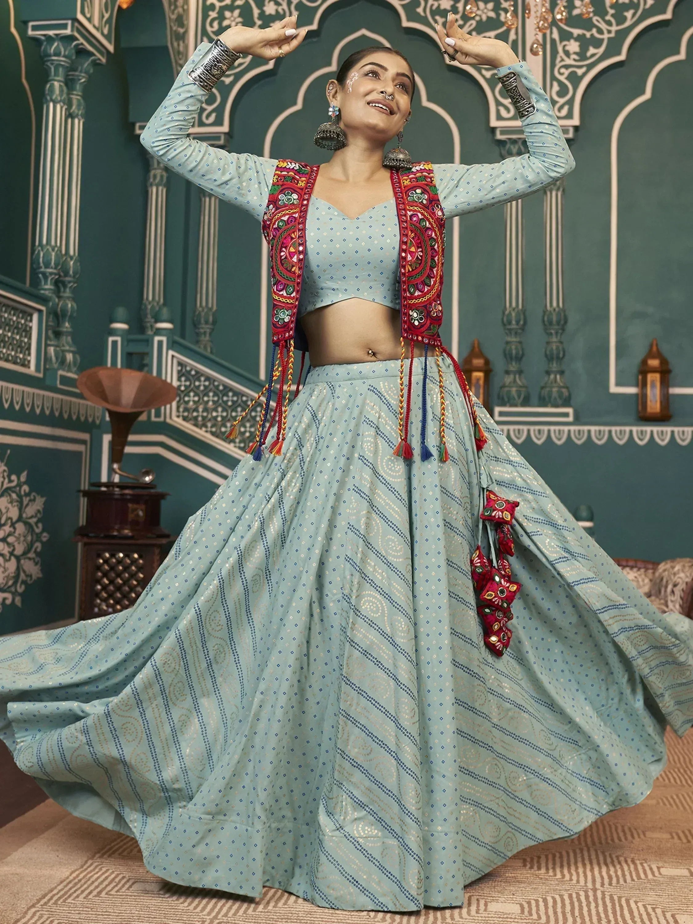 Woman dancing in light blue embroidered lehenga choli with red mirror work, Indian ethnic wear
