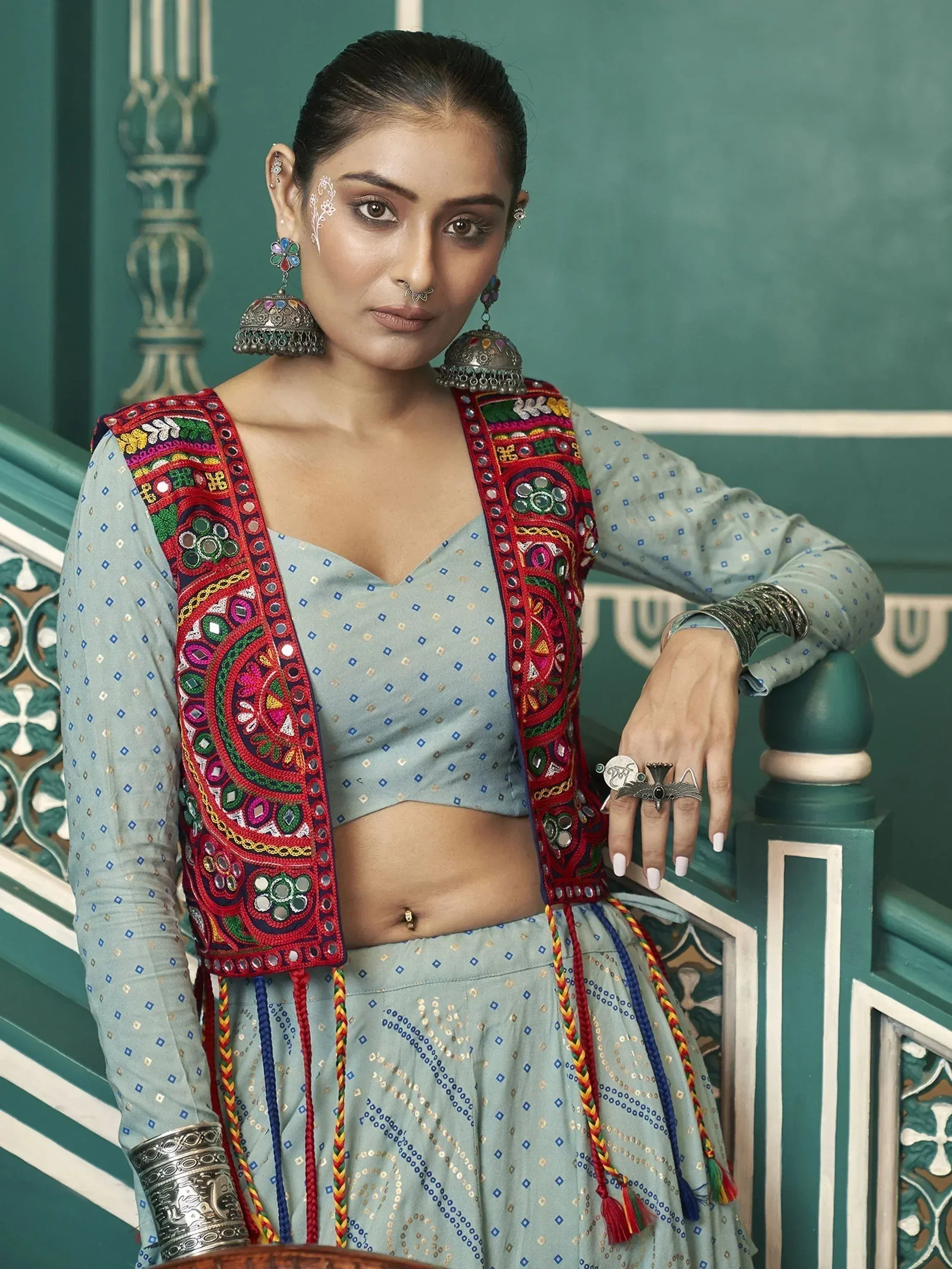 Woman in embroidered blue lehenga choli with mirror work, jhumka earrings, and traditional Indian jewelry