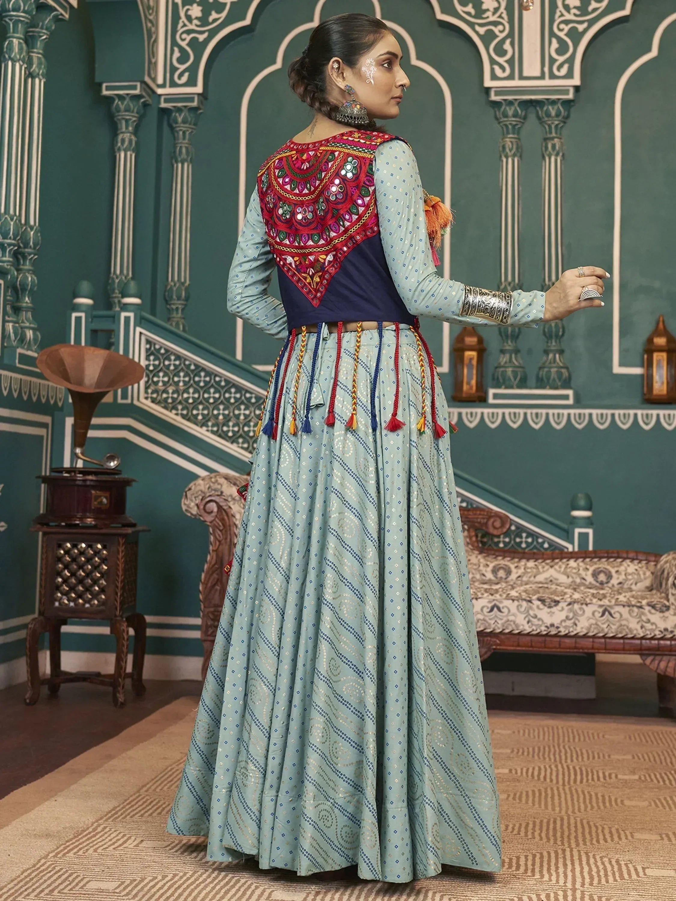 Woman in light blue embroidered ethnic gown with mirror work and tassels, traditional Indian wear