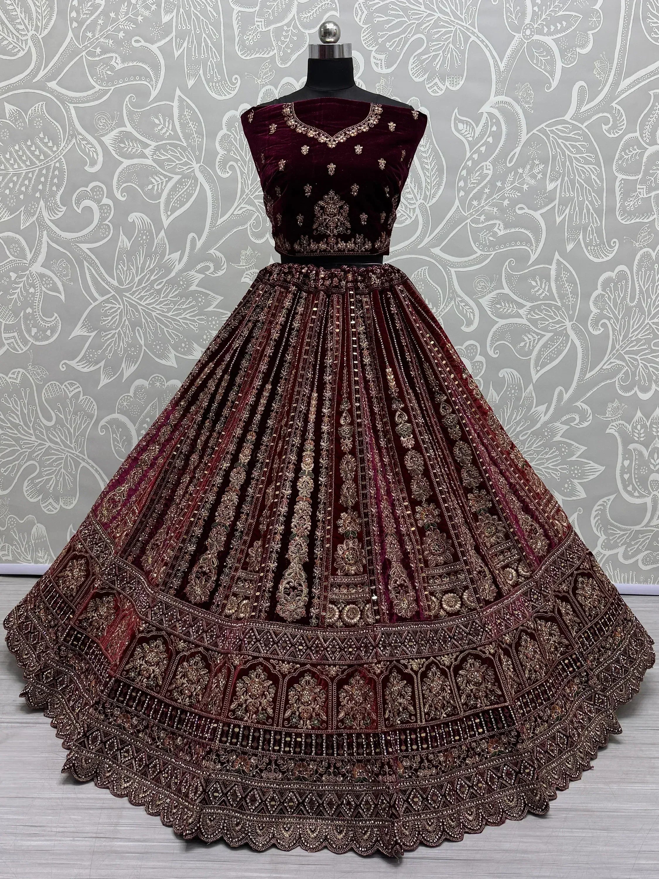 Burgundy velvet lehenga choli with heavy gold embroidery, perfect for Indian weddings and festive occasions.