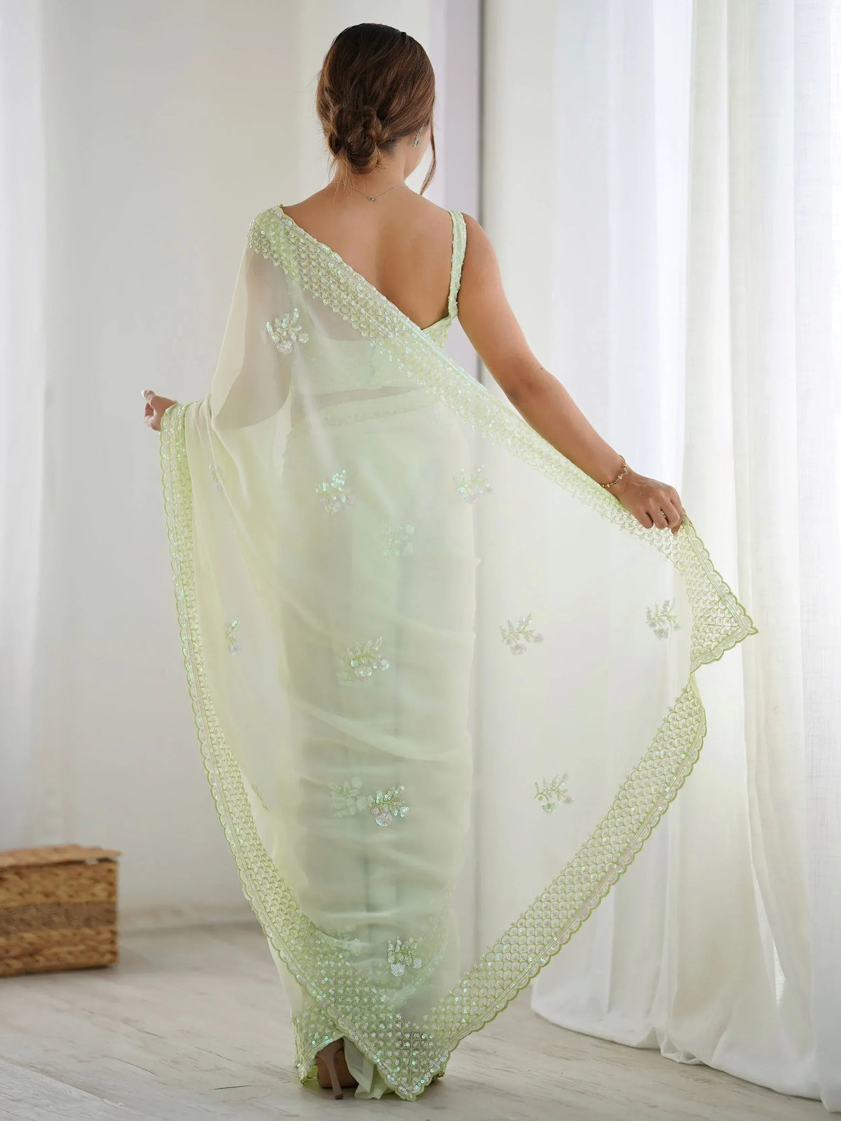 Light green sequin-embellished saree with floral motifs and scalloped border, back view