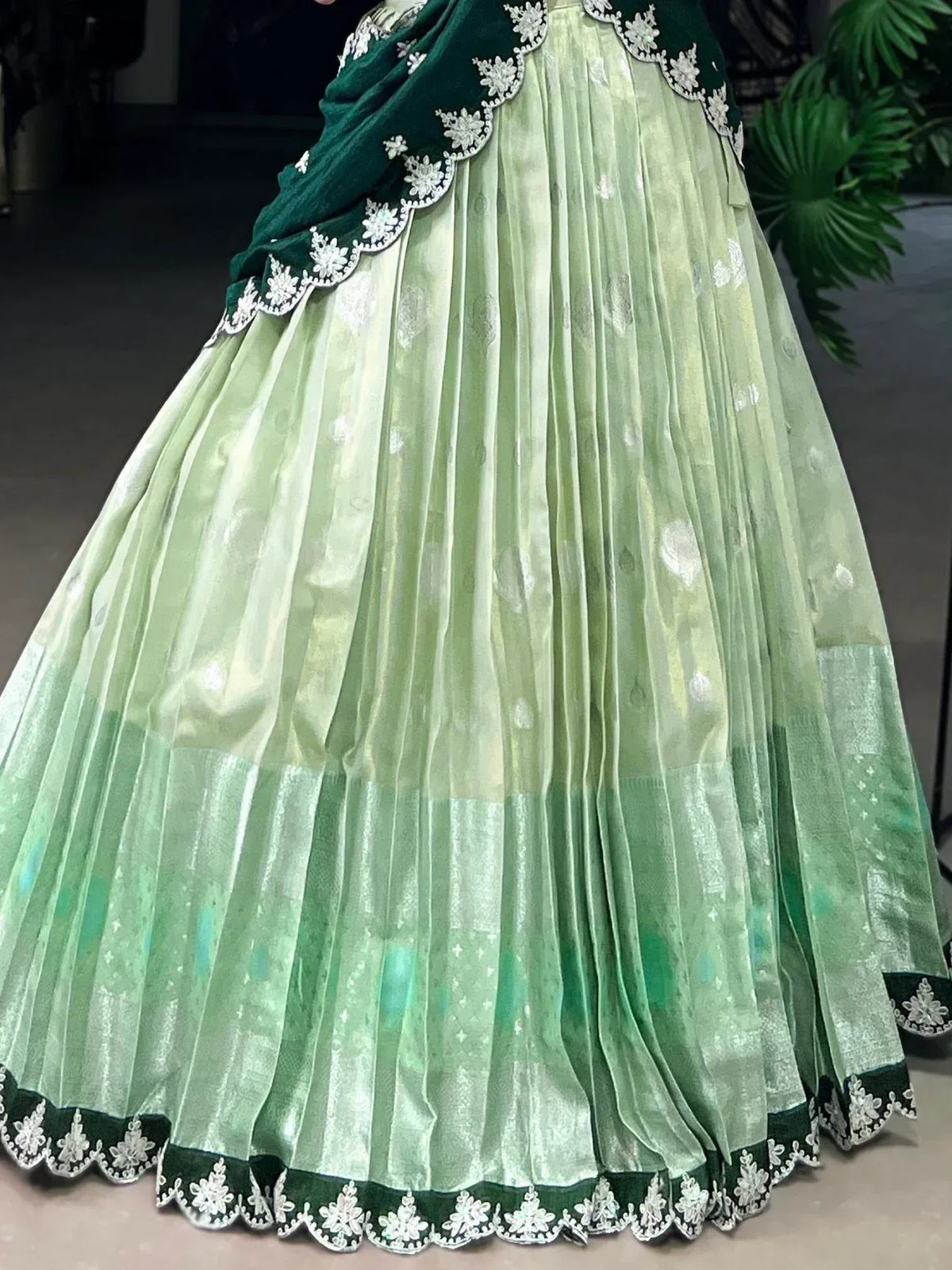 Light green pleated lehenga with dark green velvet dupatta, floral embroidery, and scalloped hem for ethnic wear.