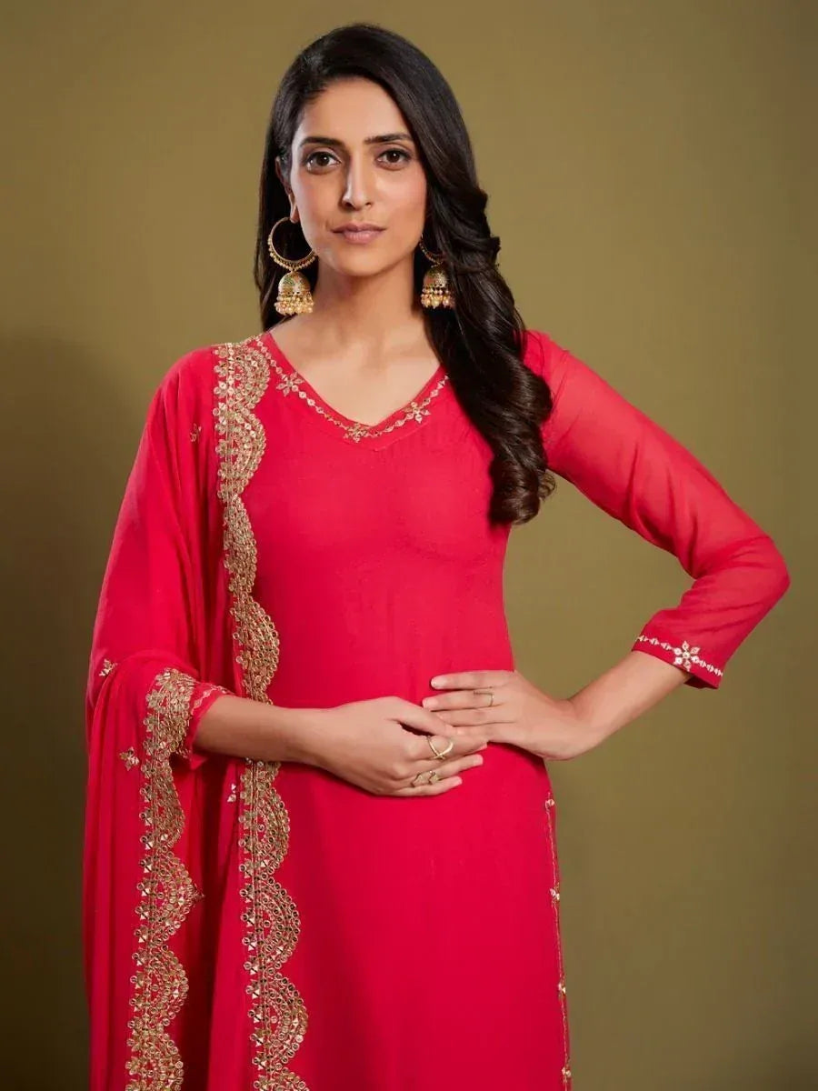 Woman in a red embroidered salwar kameez with gold dupatta and statement earrings