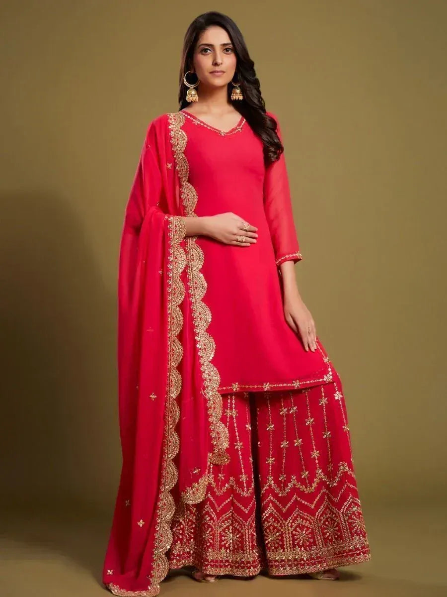 Woman wearing a red designer palazzo suit with gold embroidery and matching dupatta