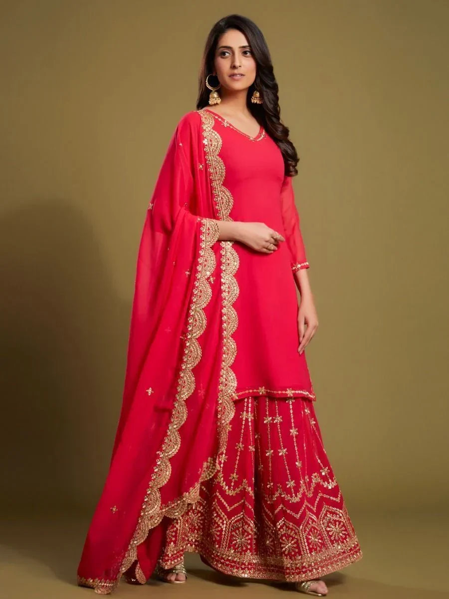 Woman wearing a bright pink sharara suit with gold embroidery and matching dupatta