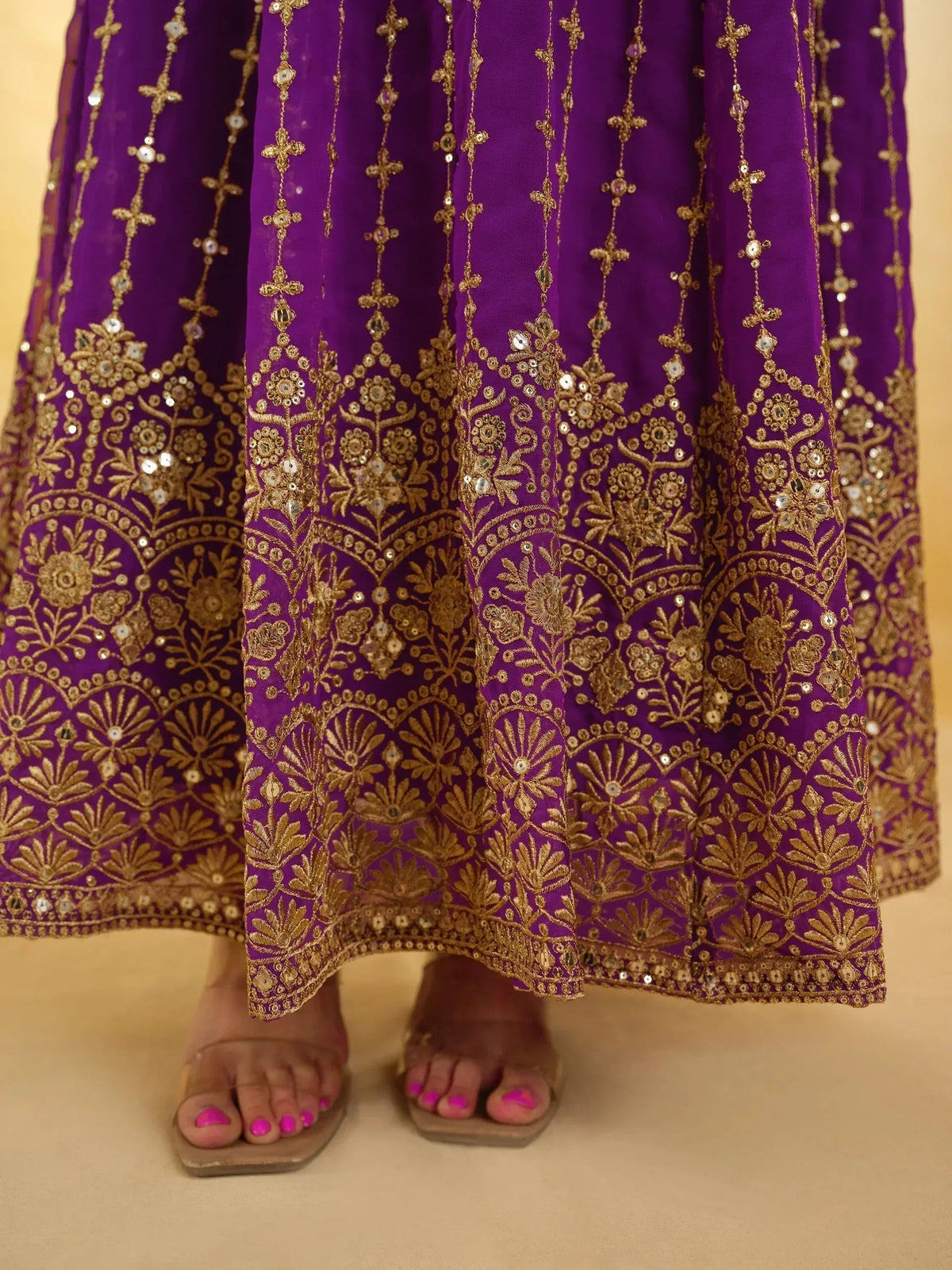 Purple ethnic gown with gold embroidery and mirror work, perfect for Indian festive occasions.