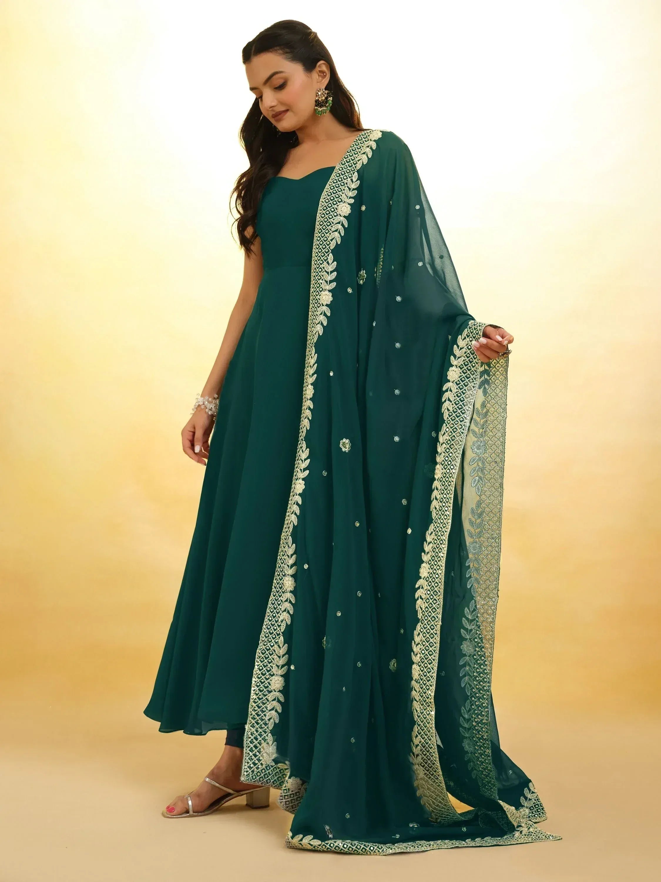 Emerald green ethnic gown with gold embroidery and sheer dupatta, perfect for Indian occasions