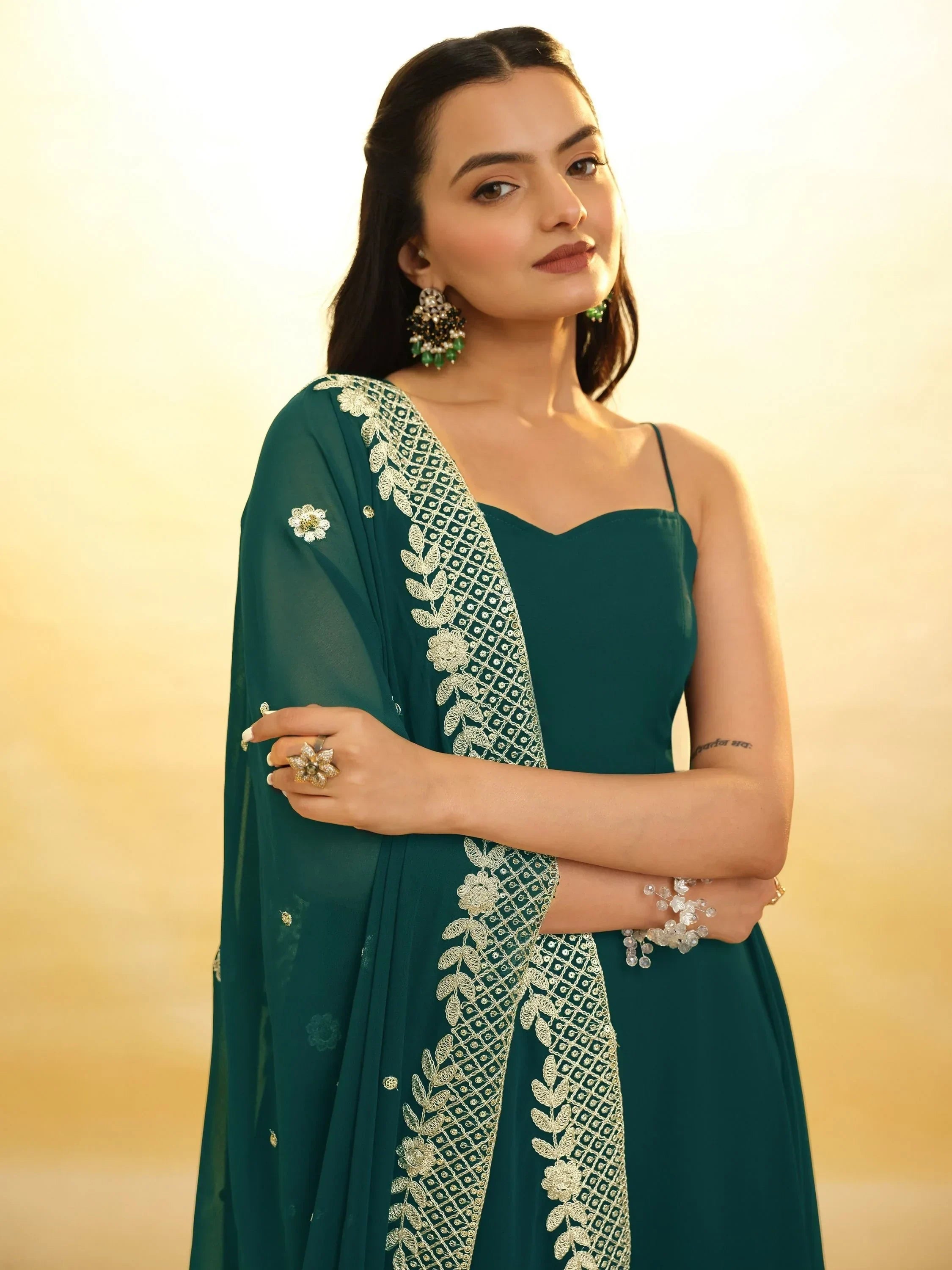 Woman in teal Indian ethnic gown with embroidered dupatta, statement earrings, and floral ring