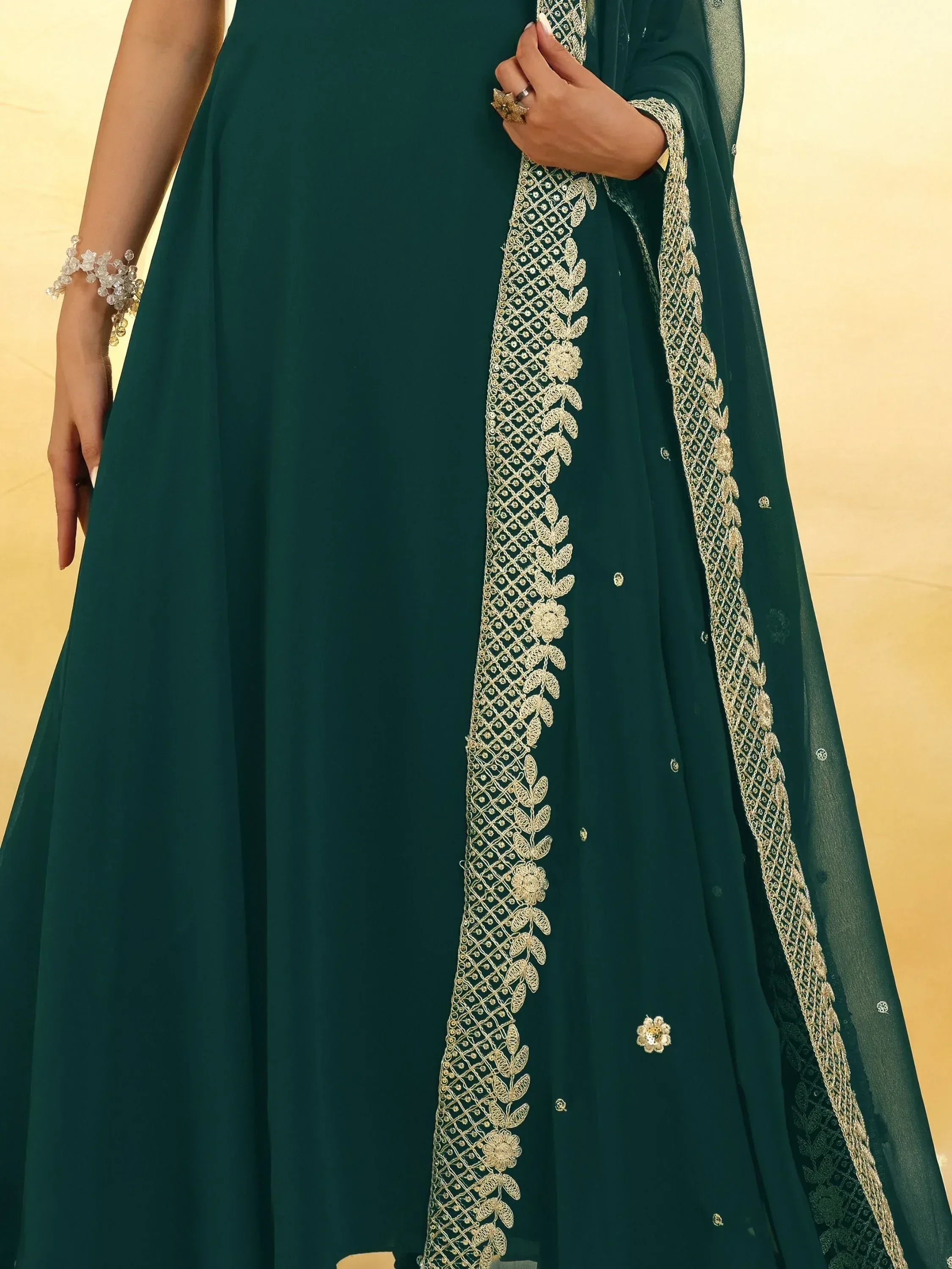 Emerald green ethnic gown with gold floral embroidery and sheer dupatta, perfect for Indian occasions