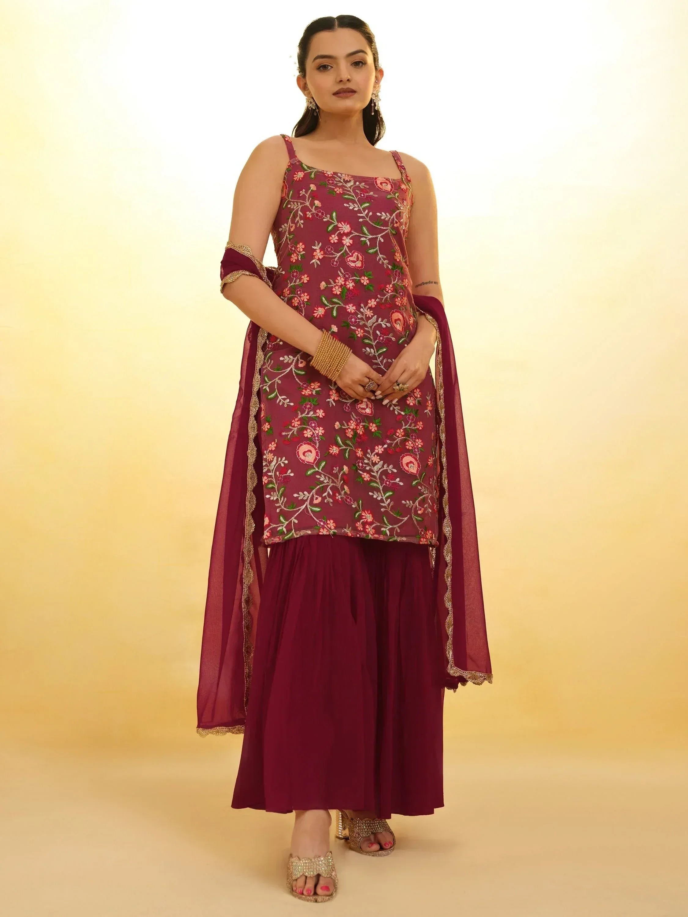Woman wearing maroon embroidered ethnic palazzo suit with dupatta, gold accessories