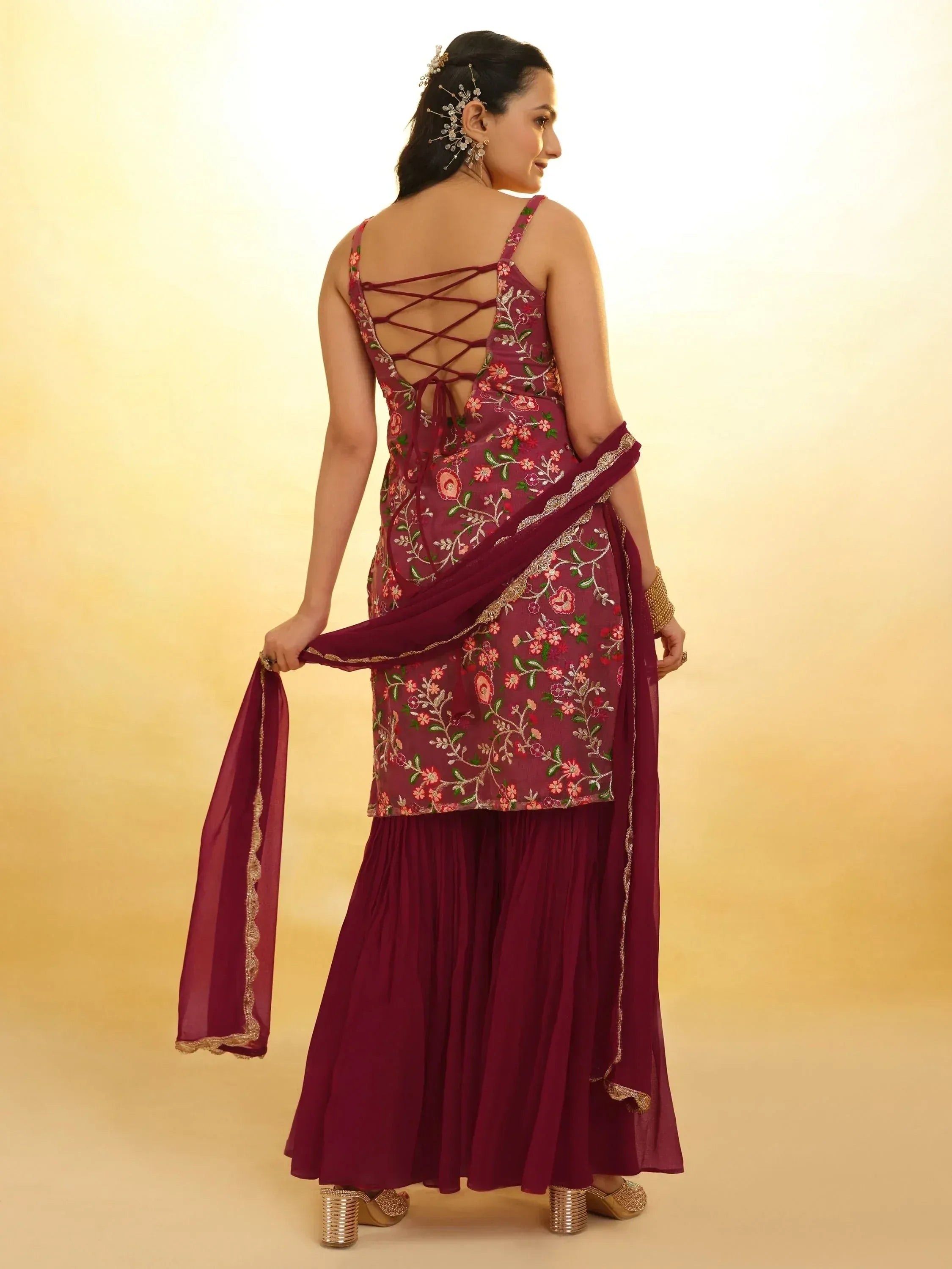 Woman in maroon floral embroidered ethnic sharara suit with dupatta, back view
