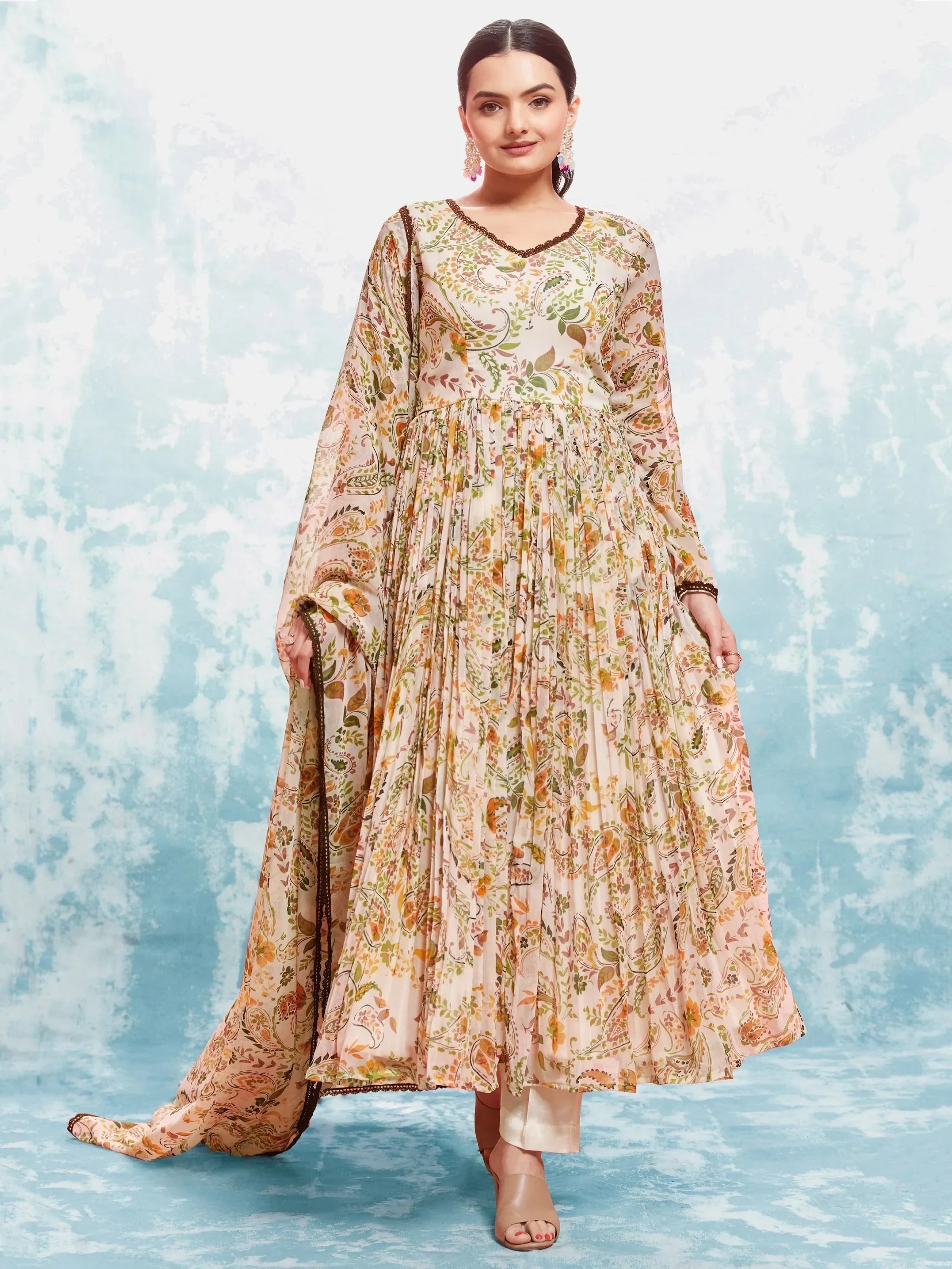 Woman wearing a floral print ethnic gown with long sleeves and dupatta, standing in studio