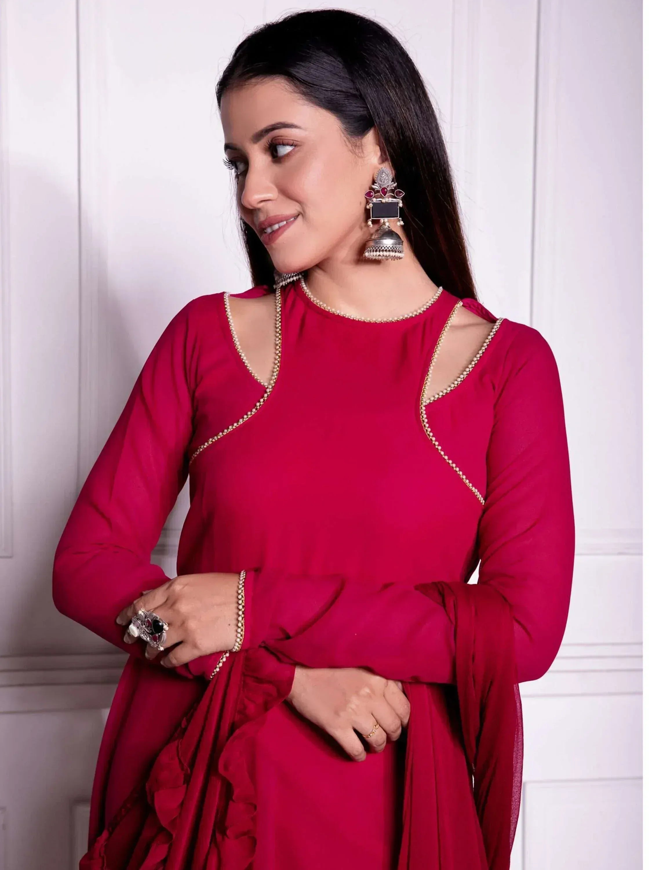 Woman in red ethnic gown with cut-out shoulders, gold trim, and jhumka earrings