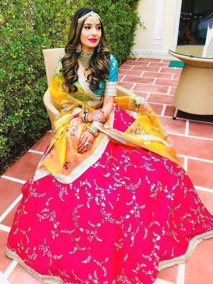 Woman in vibrant pink embroidered lehenga choli with floral dupatta, styled for Indian ethnic wear