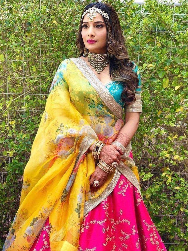 Woman in vibrant yellow and pink floral lehenga choli with gold embroidery, traditional Indian ethnic wear