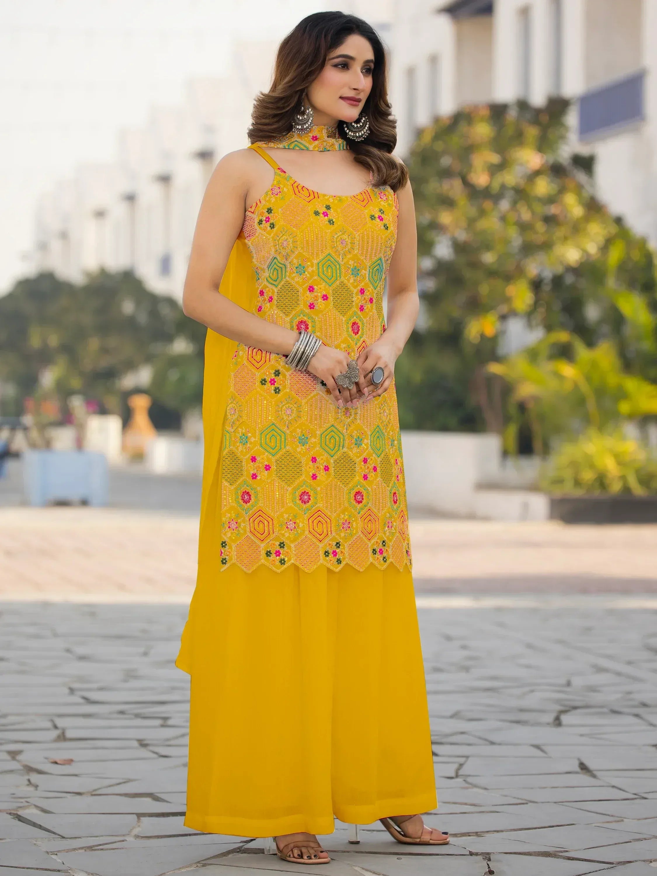 Yellow embroidered ethnic gown with floral patterns and matching palazzo pants, styled with choker and jhumkas