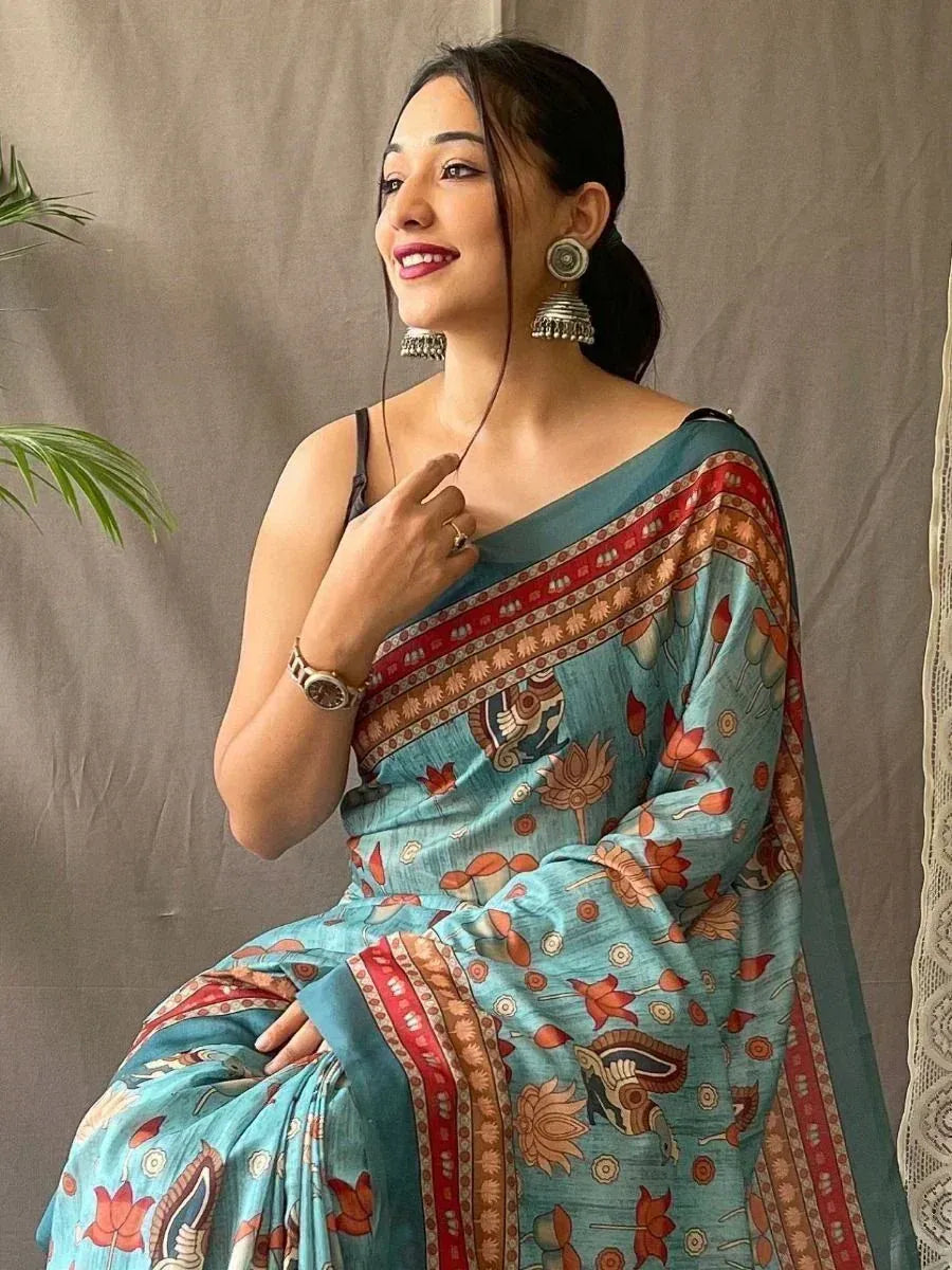 Elegant turquoise saree with floral and tribal prints, paired with traditional earrings
