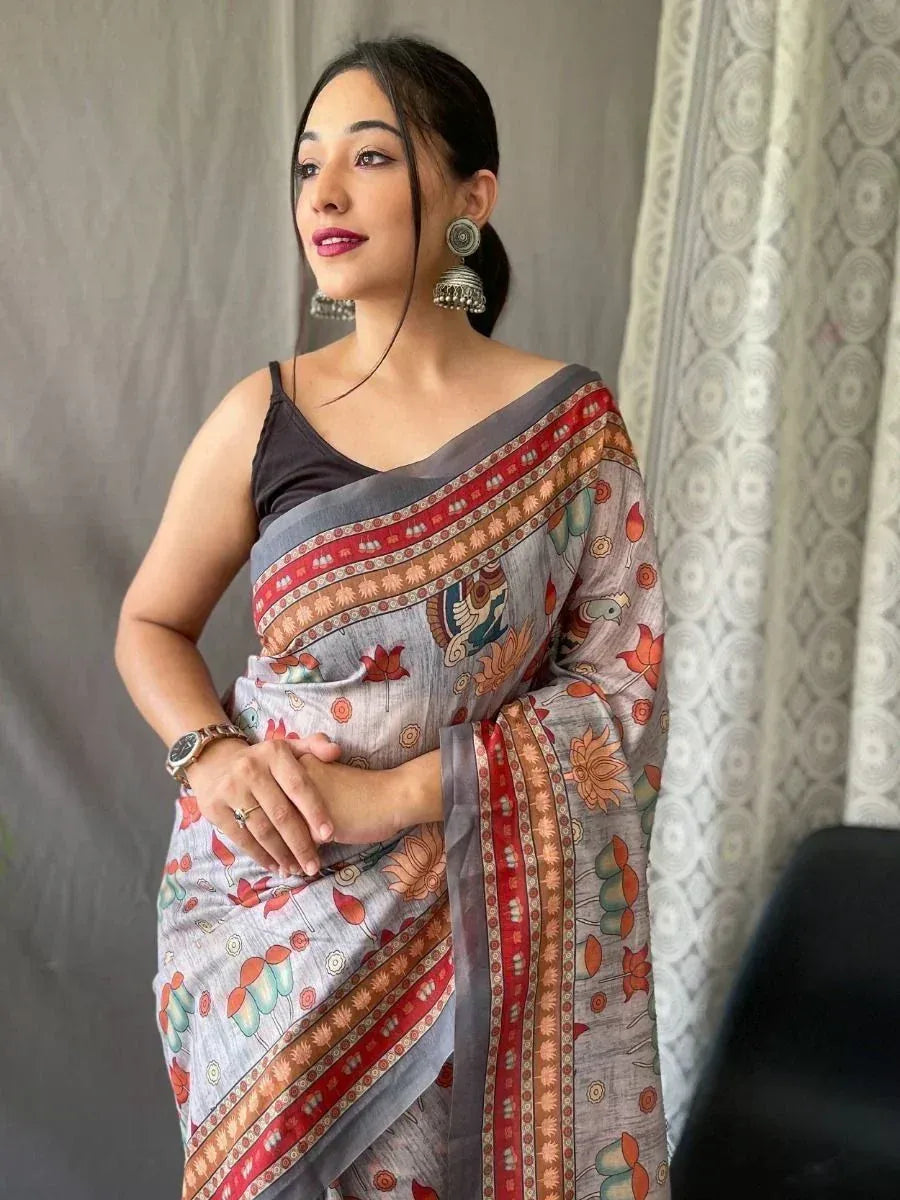 Woman wearing floral printed saree with ethnic border, paired with black blouse and traditional earrings
