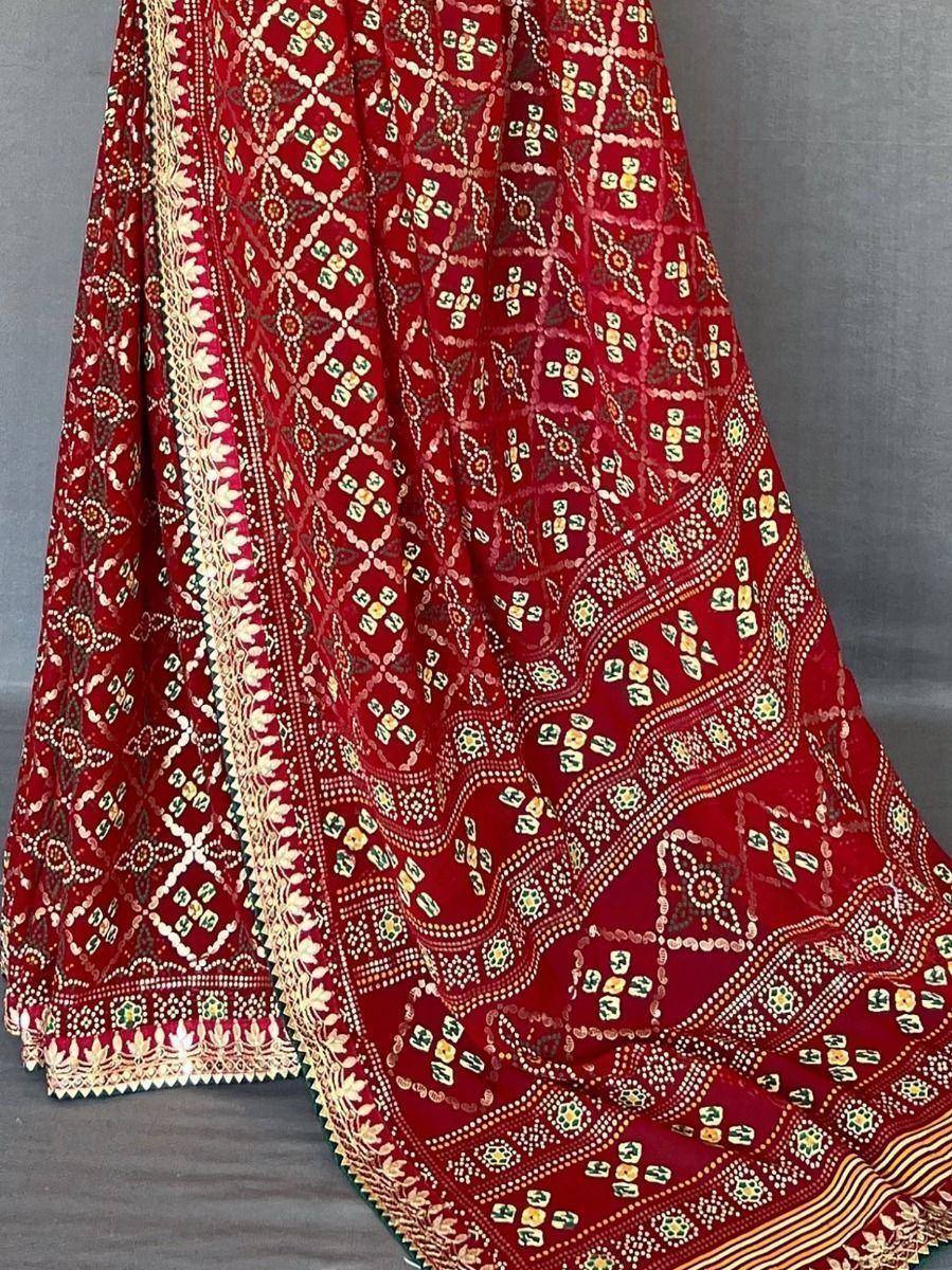 Red ethnic lehenga with intricate gold and green embroidery, perfect for Indian weddings and festive occasions.