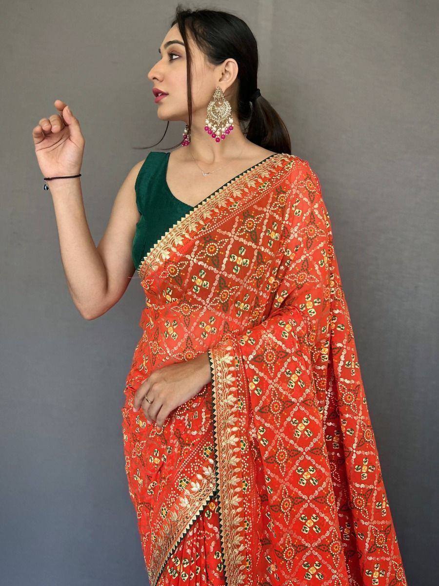 Vibrant red printed saree with gold embroidery, paired with green blouse, perfect for ethnic occasions