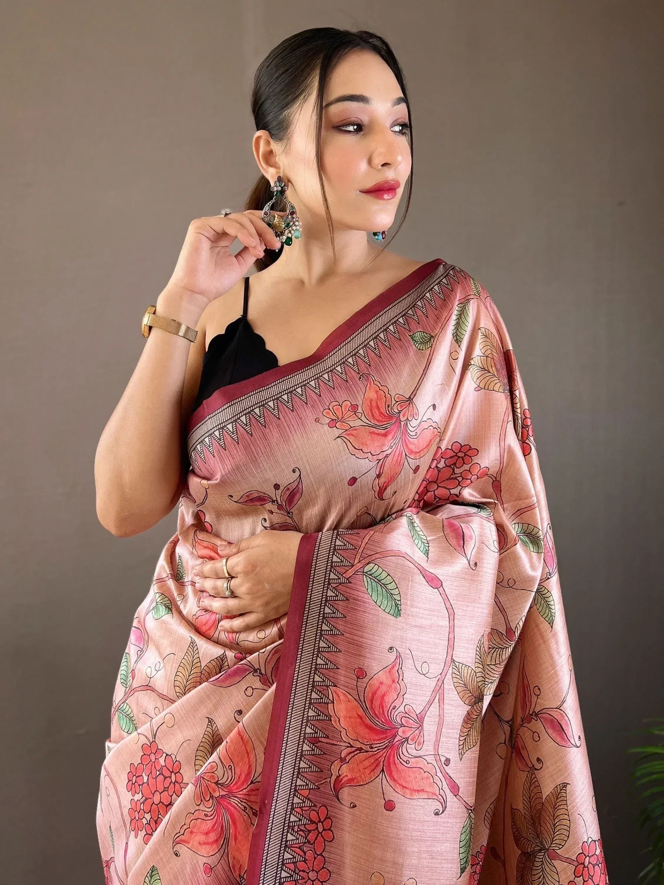 Woman in pink floral printed saree with black blouse, ethnic jewelry, and gold bangle