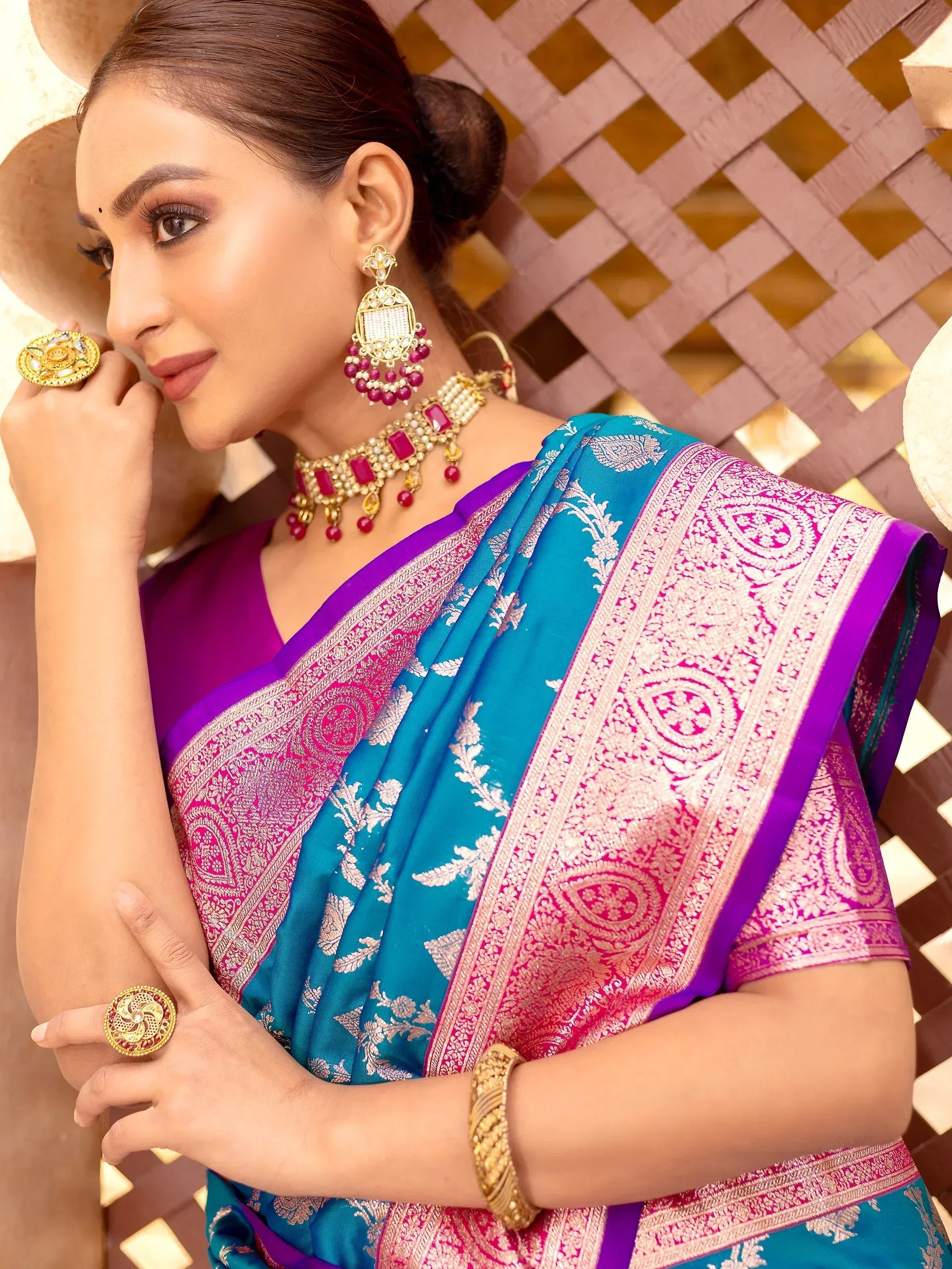 Woman in vibrant blue and pink designer saree with gold jewelry, perfect for Indian ethnic occasions