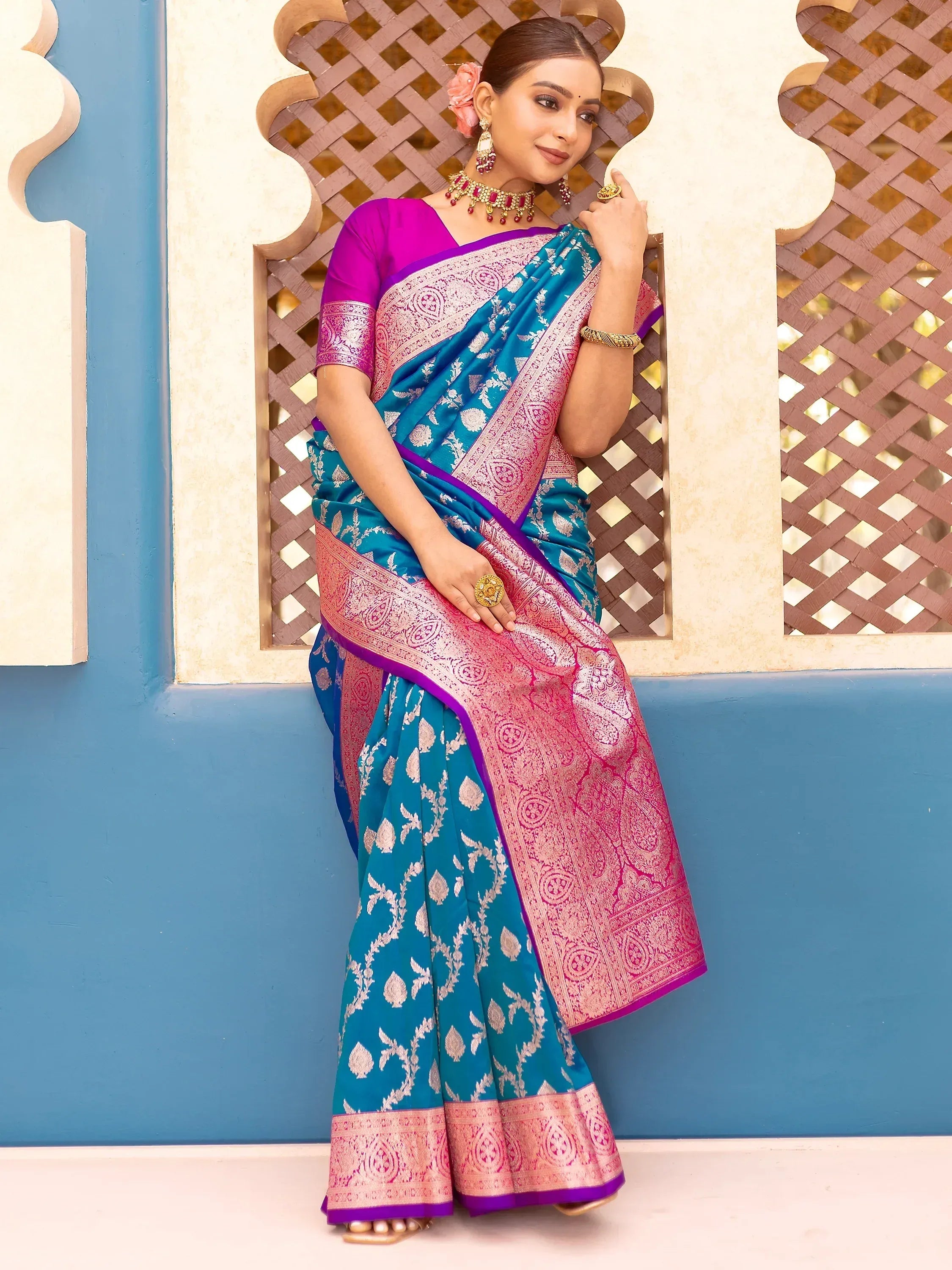 Teal and pink designer saree with gold floral motifs and purple border, paired with matching blouse for ethnic wear