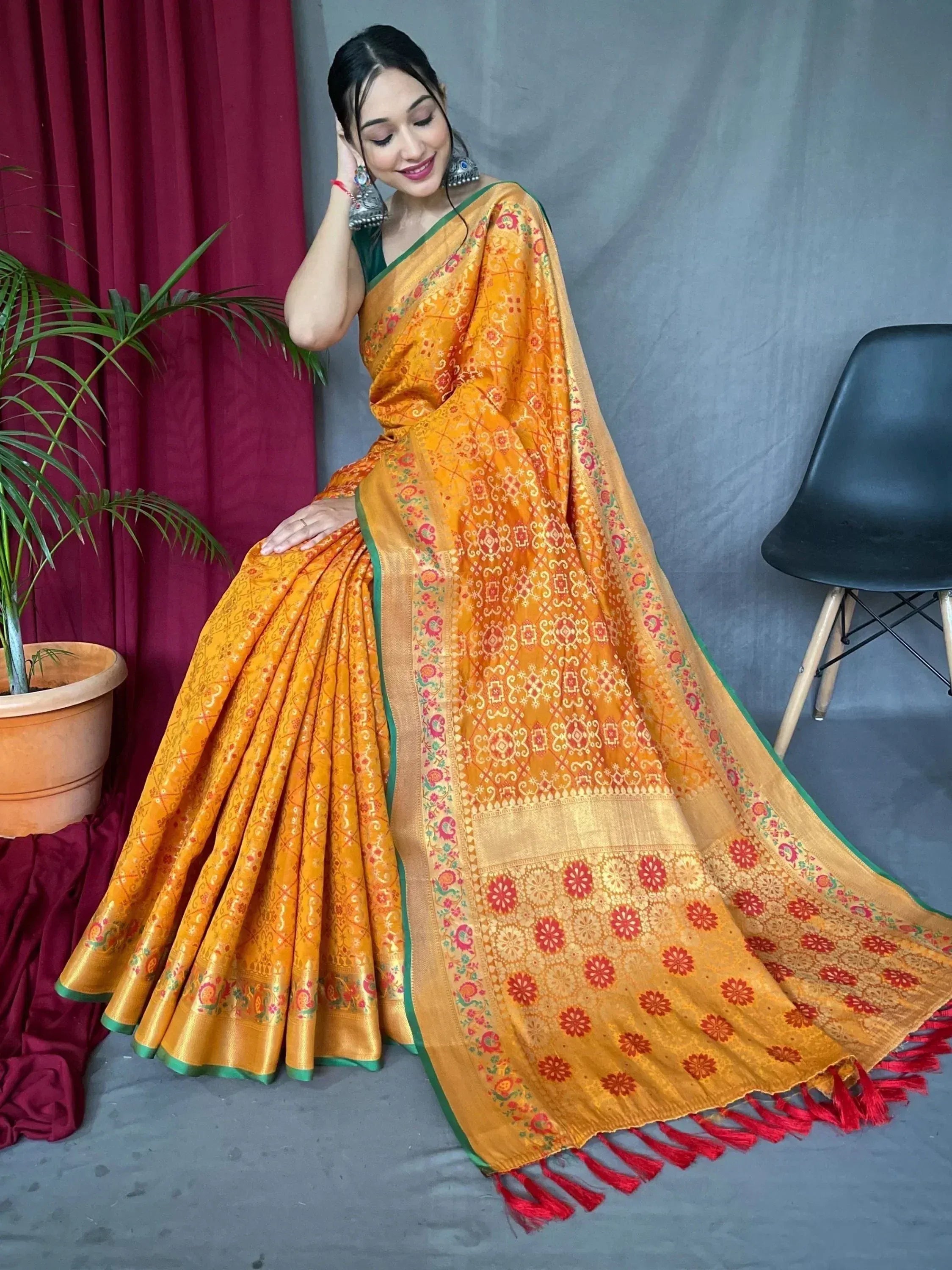 Woman in vibrant orange designer saree with floral motifs and red tassels, perfect for Indian ethnic wear