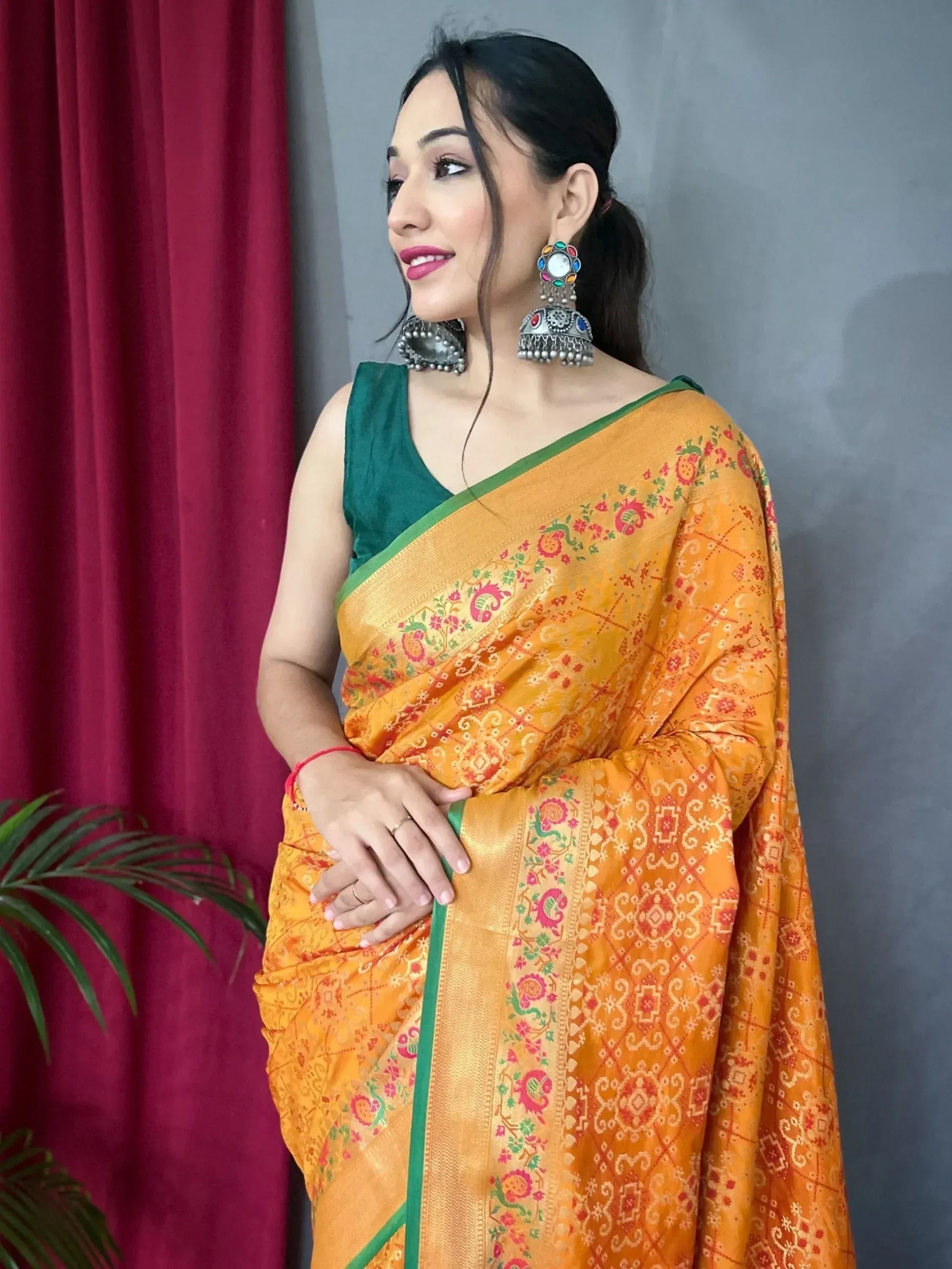 Woman in vibrant orange printed saree with green blouse, traditional ethnic wear for Indian occasions