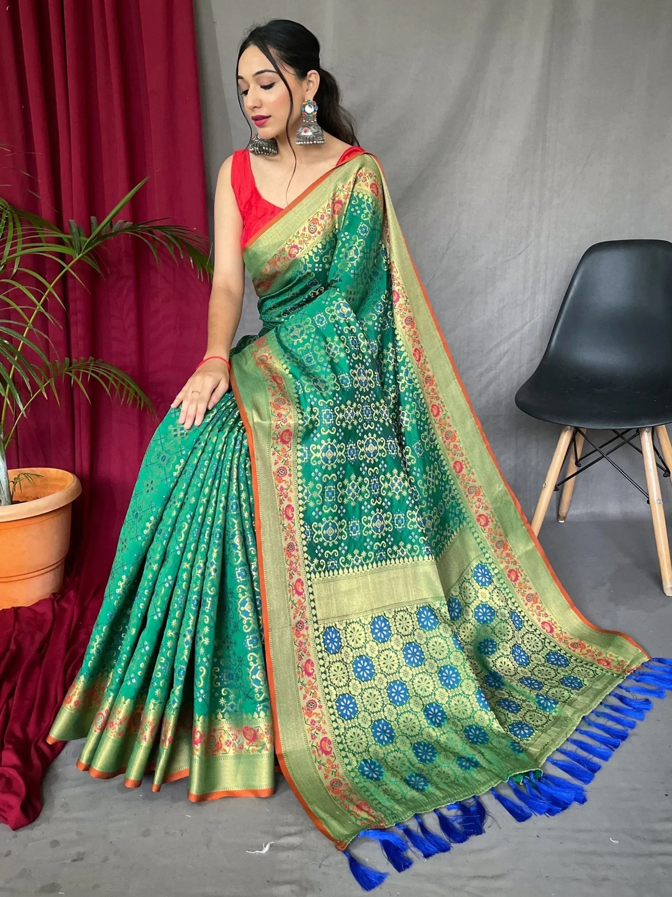 Green printed saree with gold border and blue tassels, paired with red blouse, ethnic Indian wear