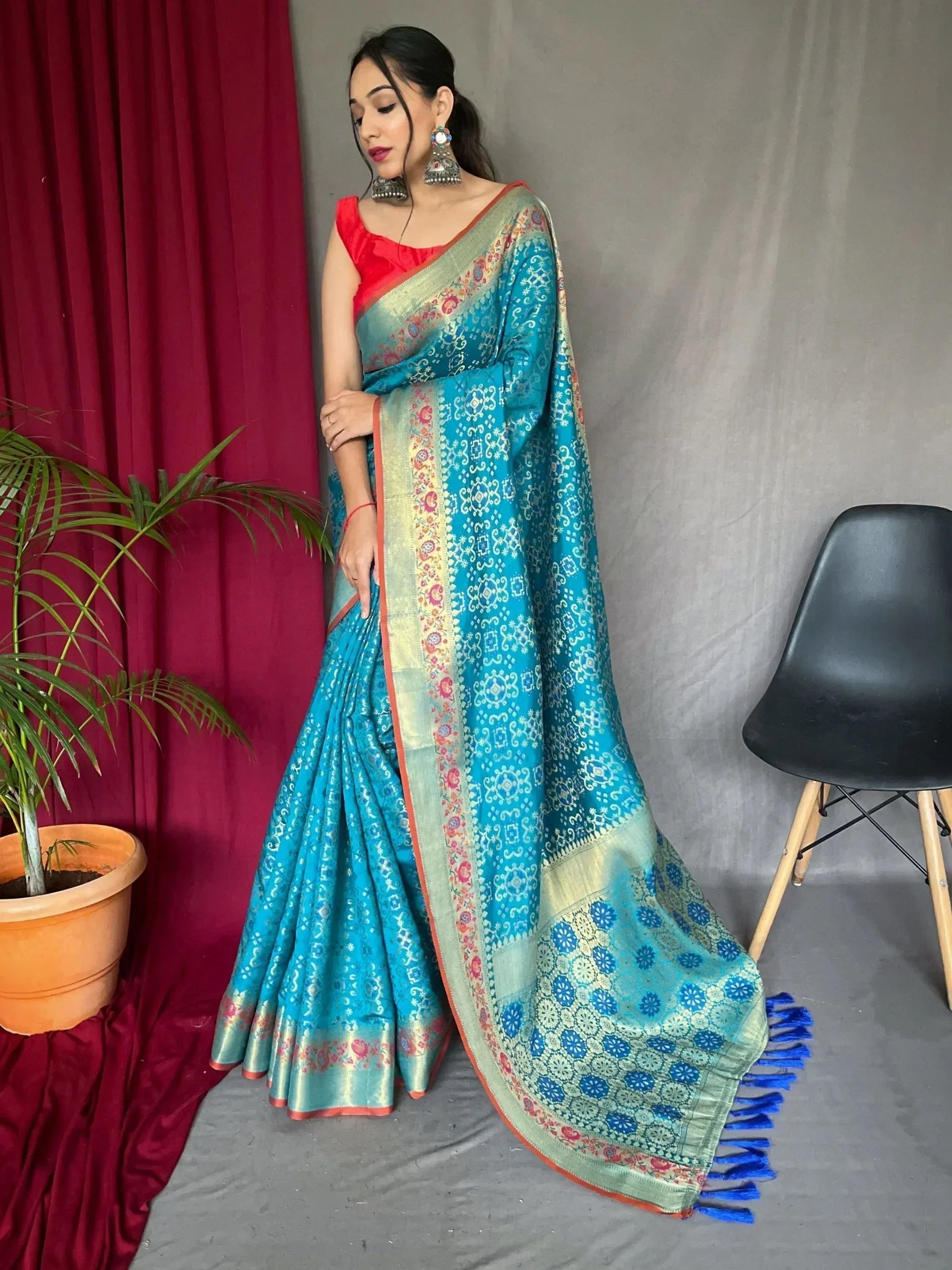 Turquoise designer saree with gold border and floral motifs, paired with red blouse, ideal for ethnic occasions
