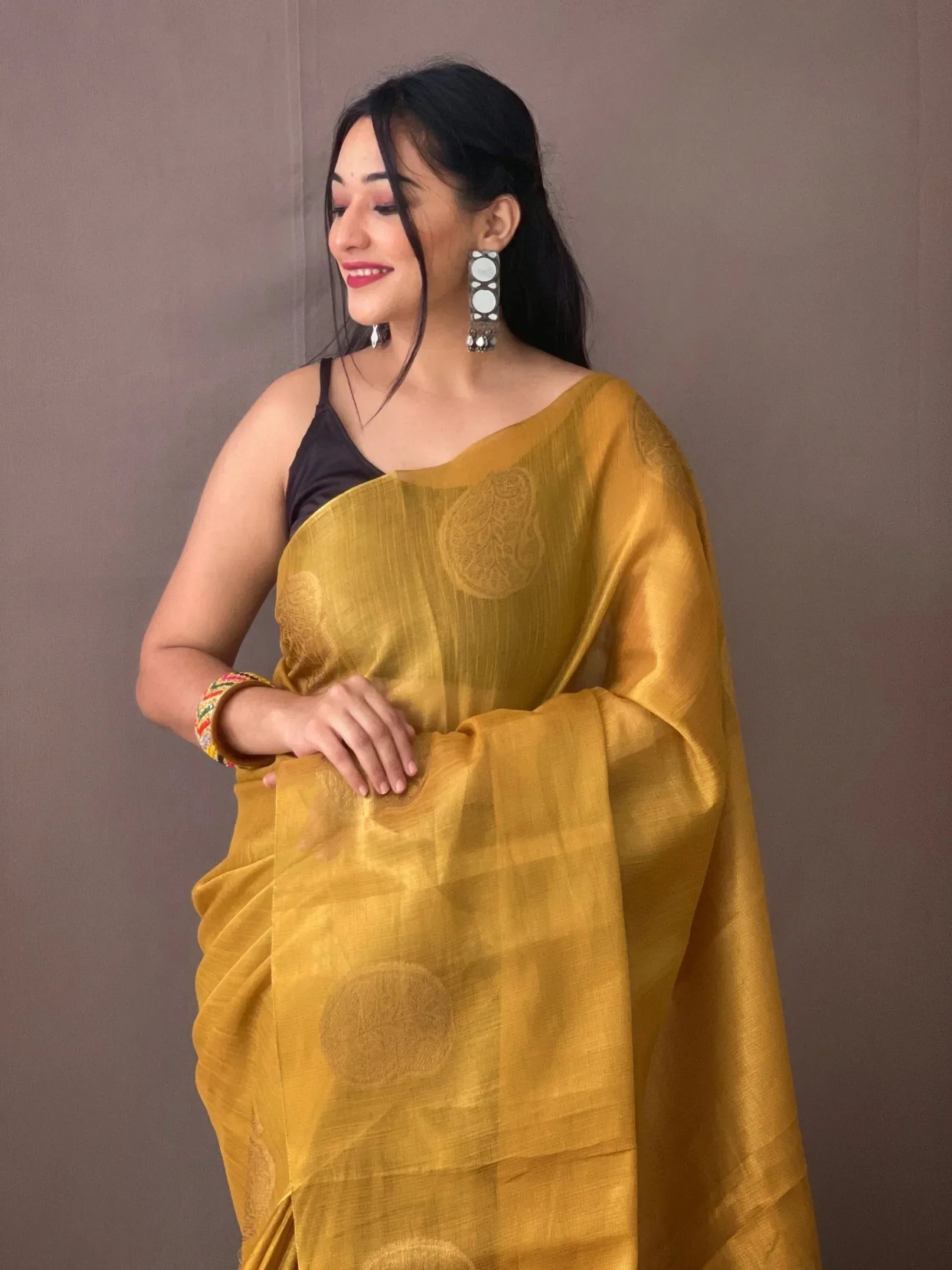 Woman in mustard yellow ethnic saree with black blouse and statement earrings