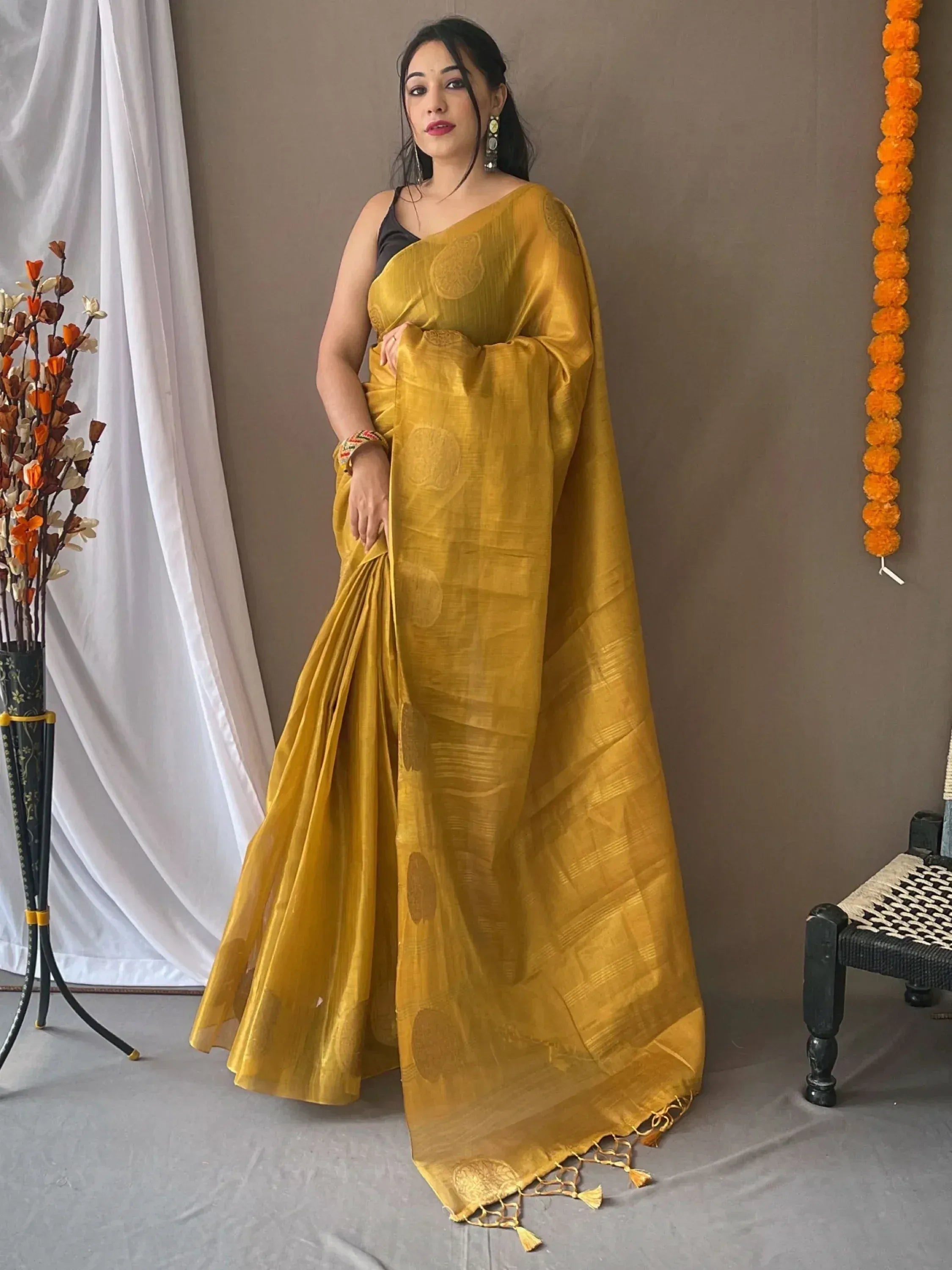 Woman in mustard yellow designer saree with circular motifs and tassels, styled for ethnic occasions