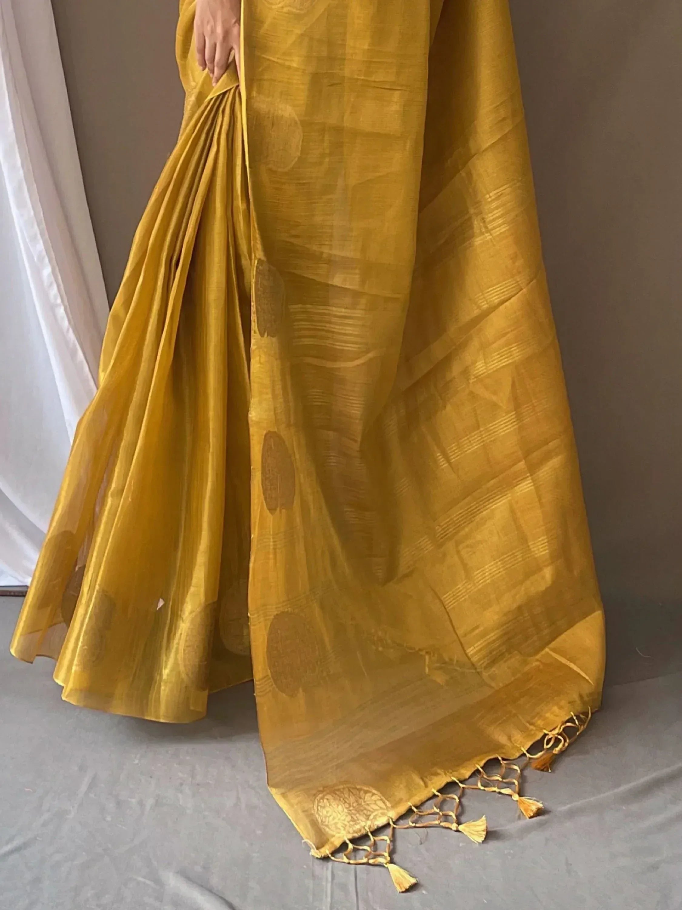 Mustard yellow ethnic saree with woven motifs and tassel border, ideal for Indian occasions