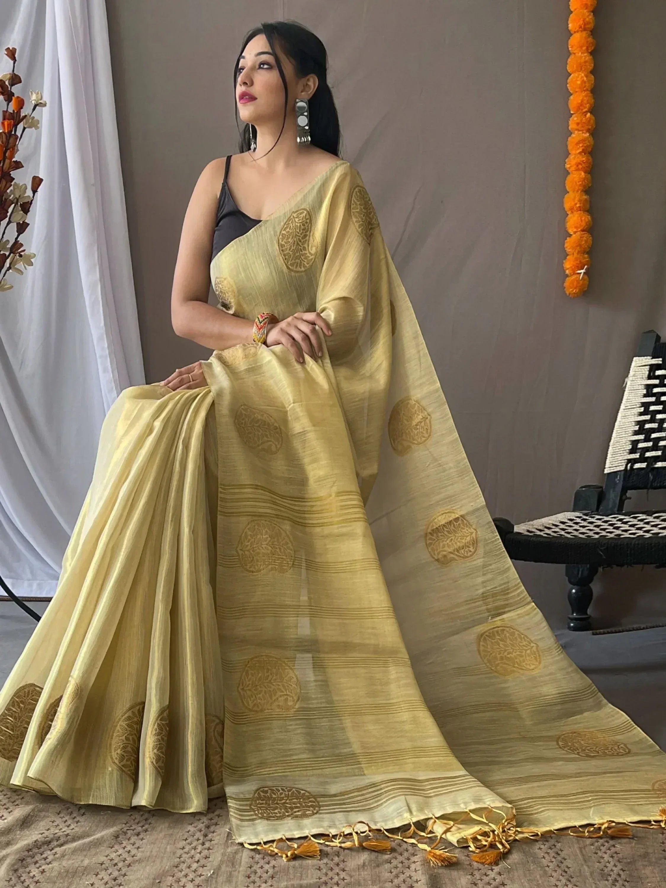 Elegant yellow saree with gold leaf motifs and tassels, styled with black blouse for Indian ethnic wear.