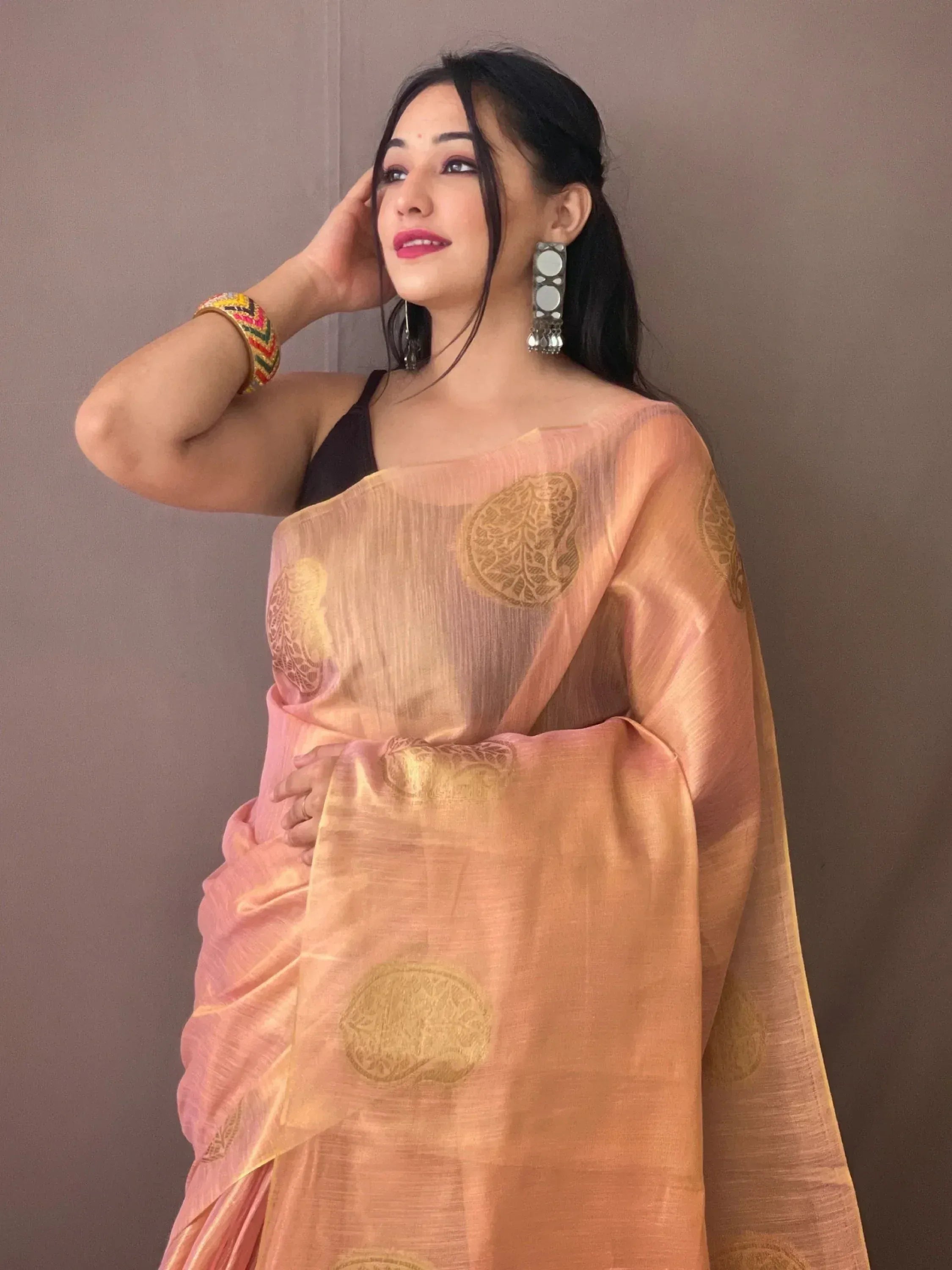 Woman in peach saree with gold paisley print, ethnic Indian wear, stylish accessories