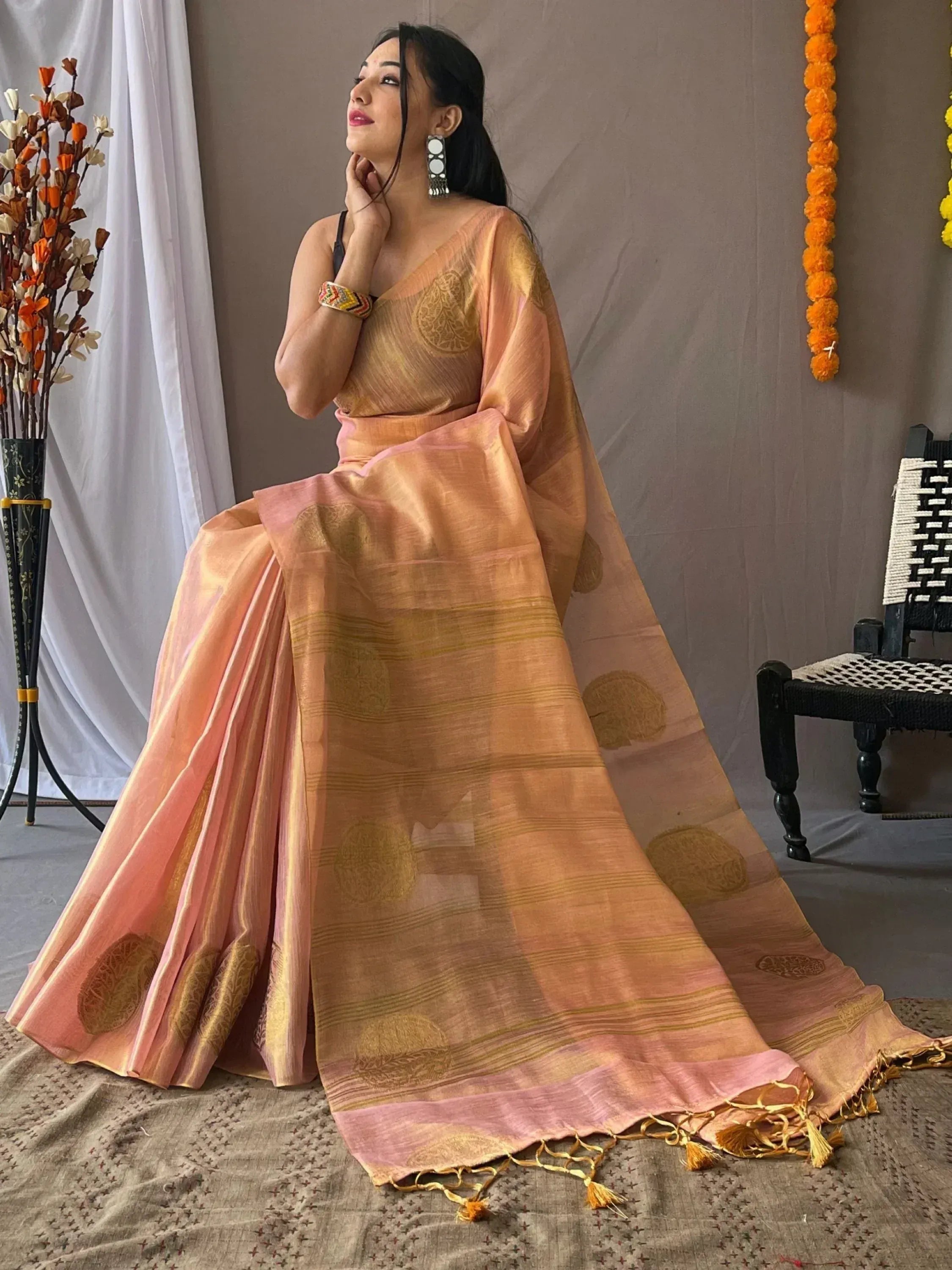 Peach and gold designer saree with woven motifs and tassels, styled for ethnic occasions